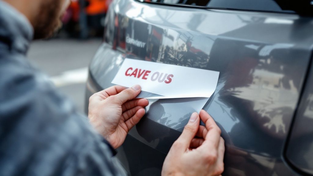 A person's hand pointing at an online sticker ordering interface on a laptop screen