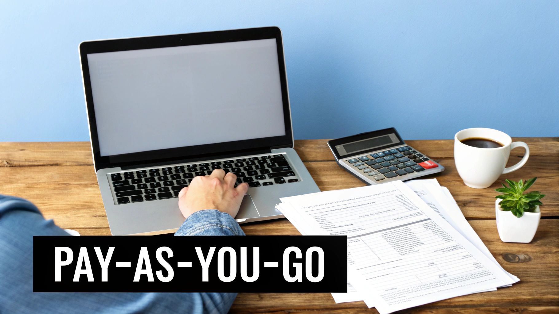 Person working on laptop with calculator and financial documents for pay-as-you-go tax payments