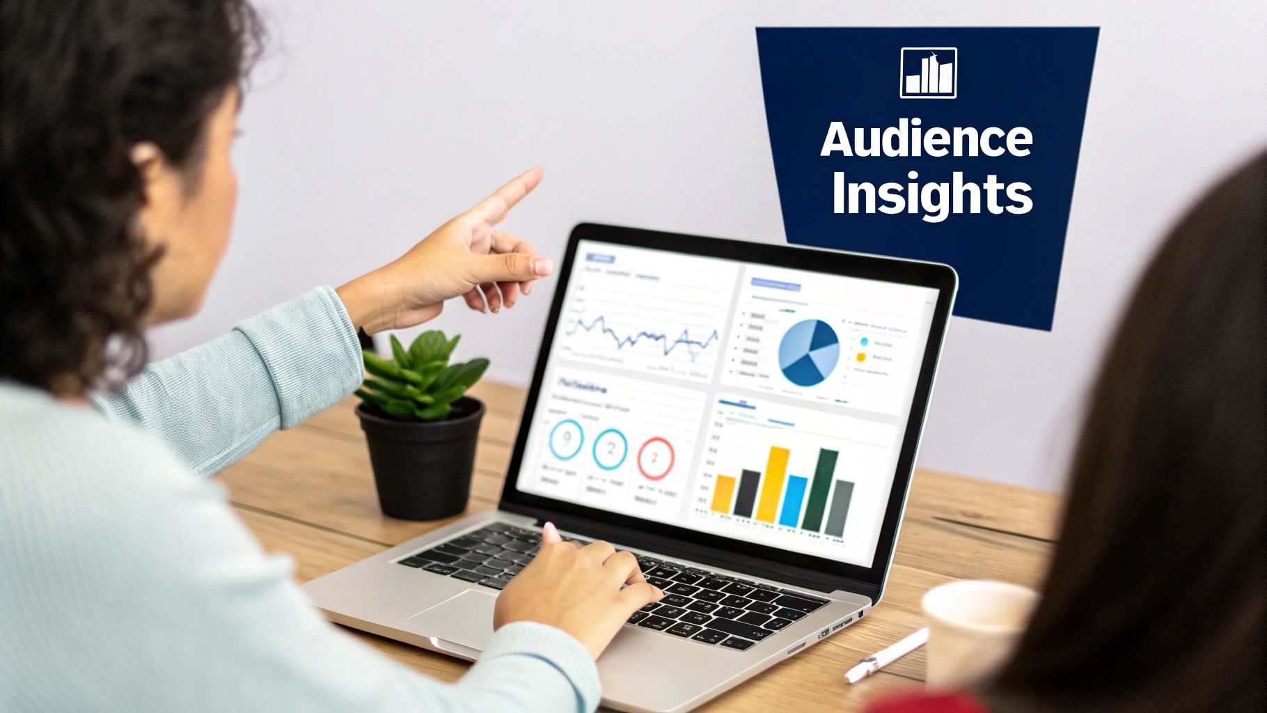 Two people analyzing audience insights data on a laptop with various charts and graphs.