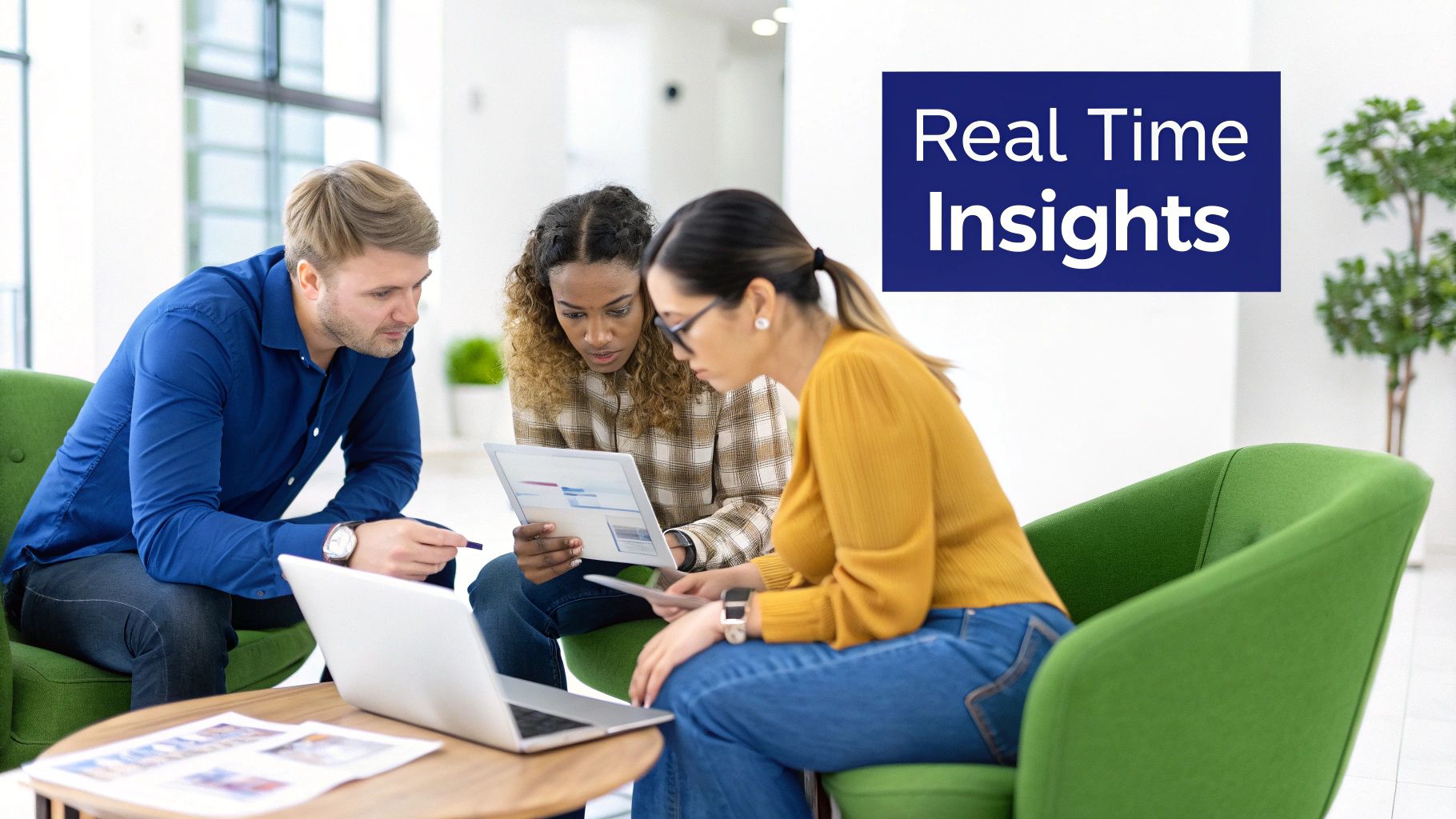 Three diverse colleagues collaborate on laptops and documents in a modern office lounge, discussing real-time insights.