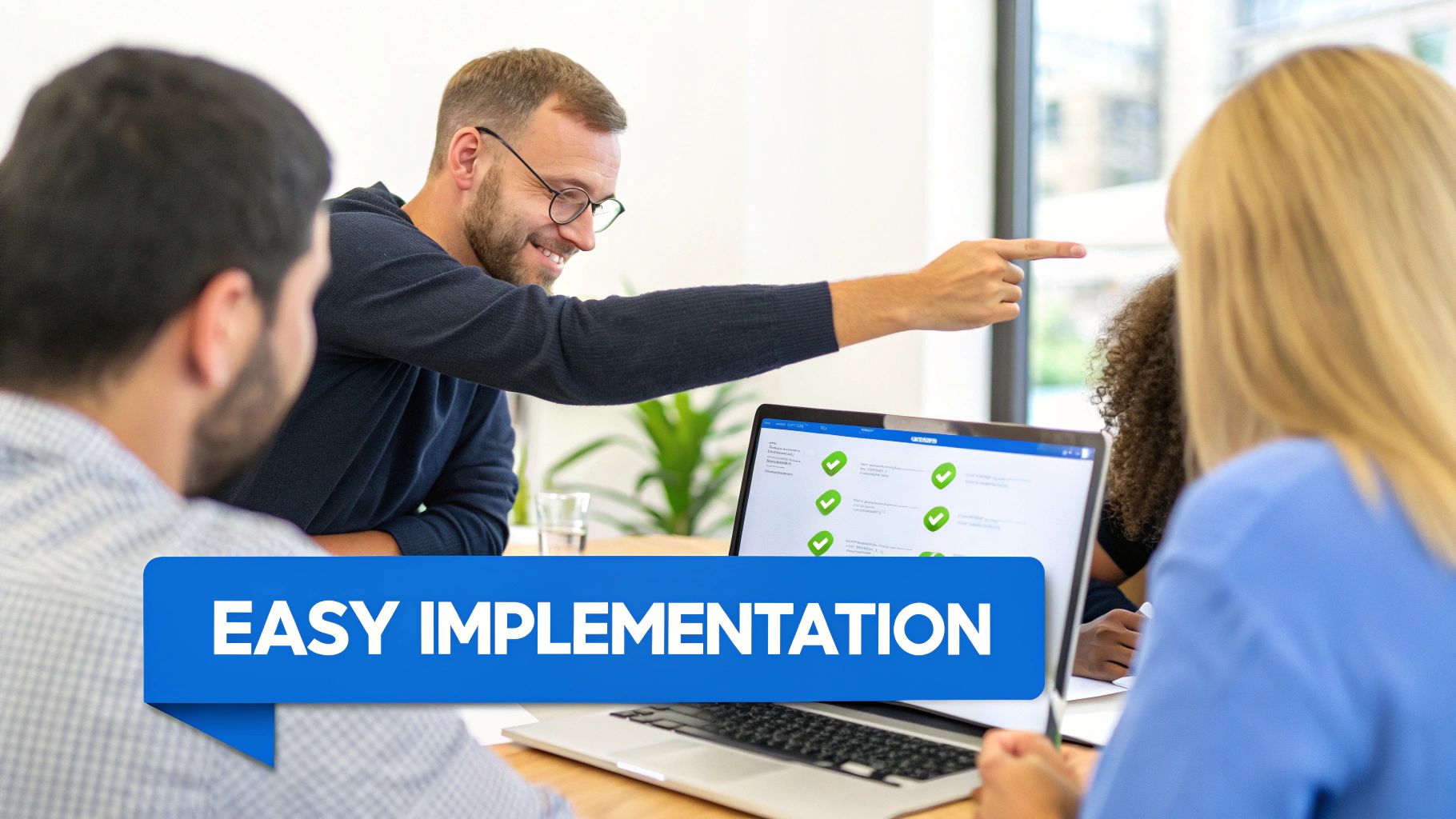 Man smiles and points at a laptop with green checkmarks, illustrating easy software implementation in a meeting.