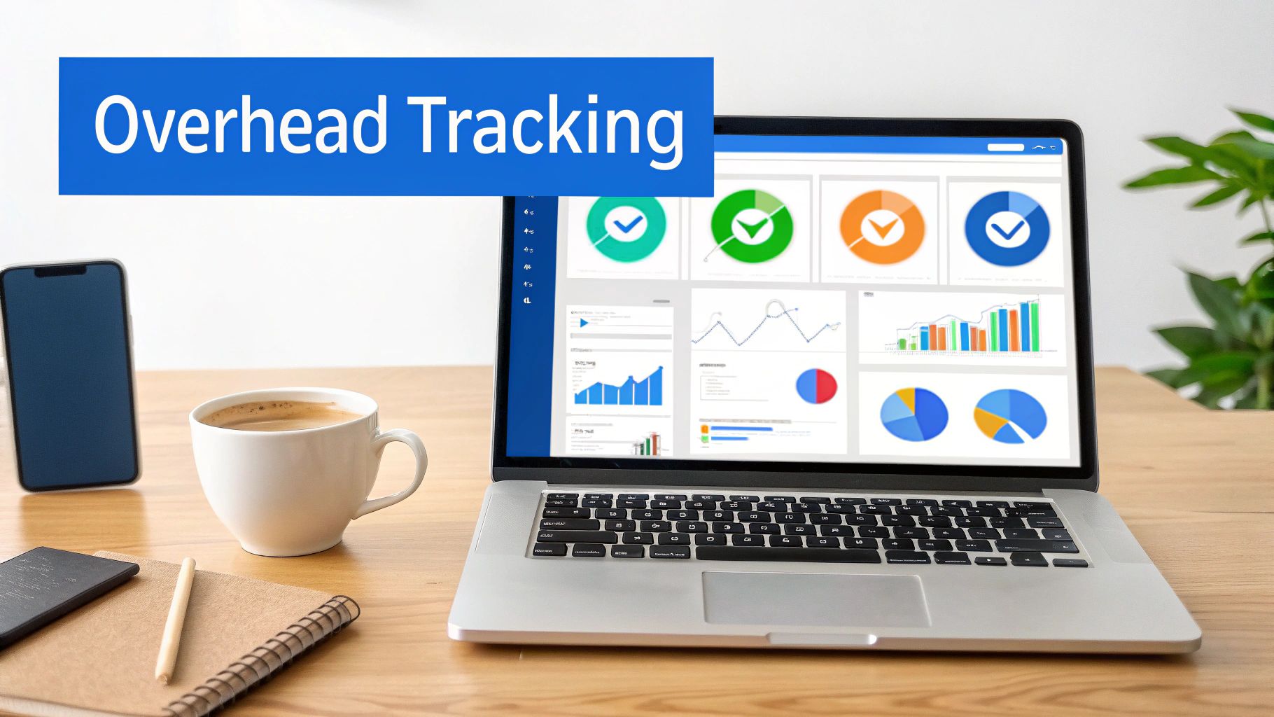 Laptop displaying an 'Overhead Tracking' dashboard with charts, graphs, phone, coffee, and notebook.