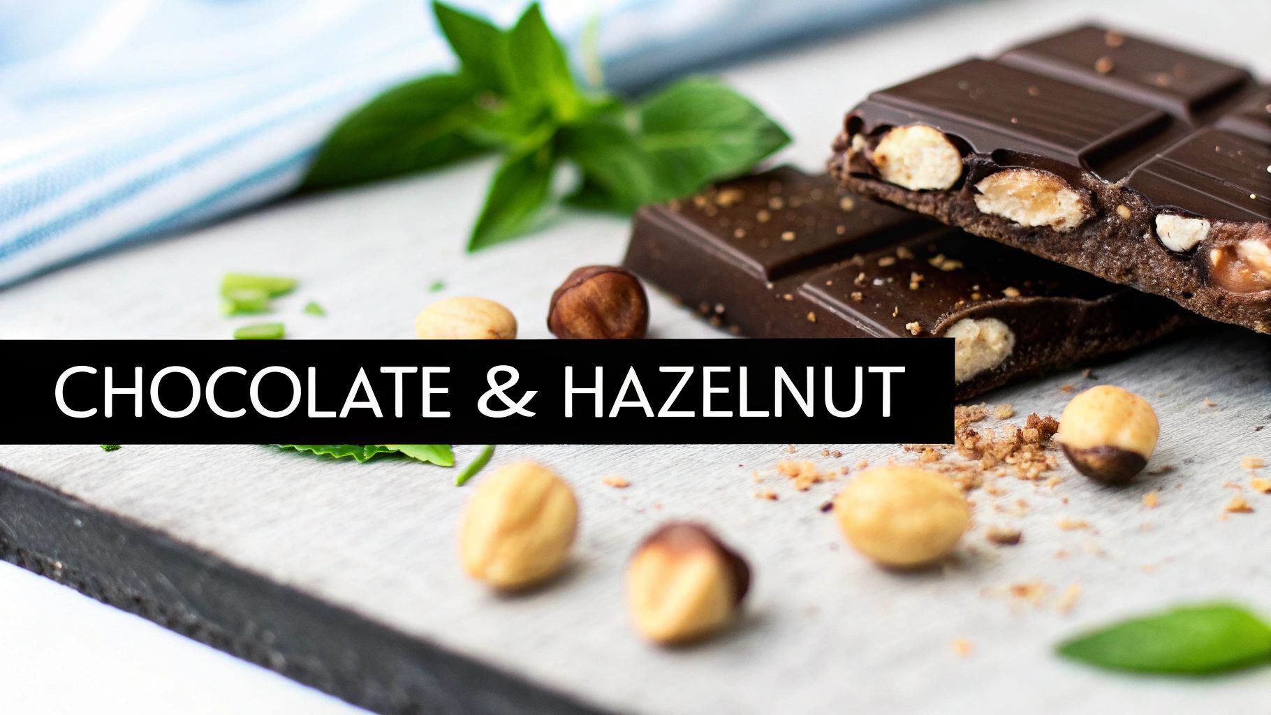 Close-up of dark chocolate bars with whole hazelnuts, scattered on a rustic surface with mint.