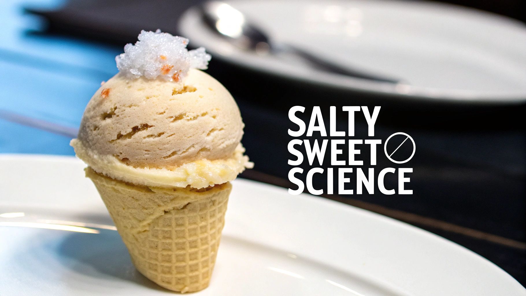 A scoop of pale ice cream in a mini waffle cone, topped with white and orange crystals, beside 'SALTY SWEET SCIENCE' text.