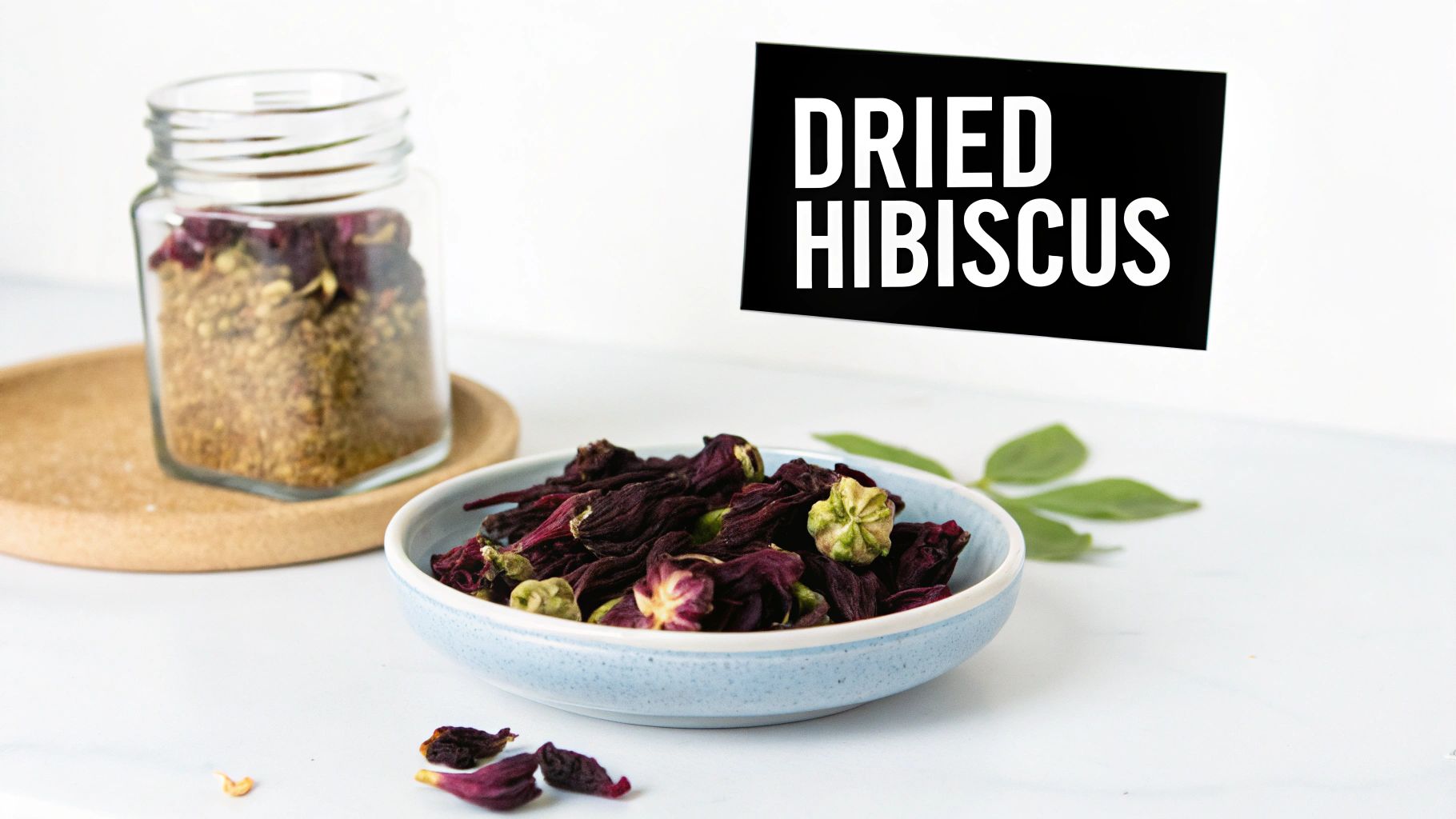 Dried hibiscus flowers in light blue ceramic bowl with glass jar on wooden board