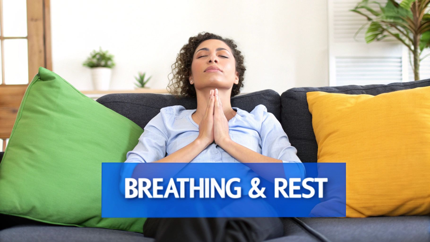 A woman with curly hair meditating on a sofa, with closed eyes and clasped hands, promoting breathing and rest.