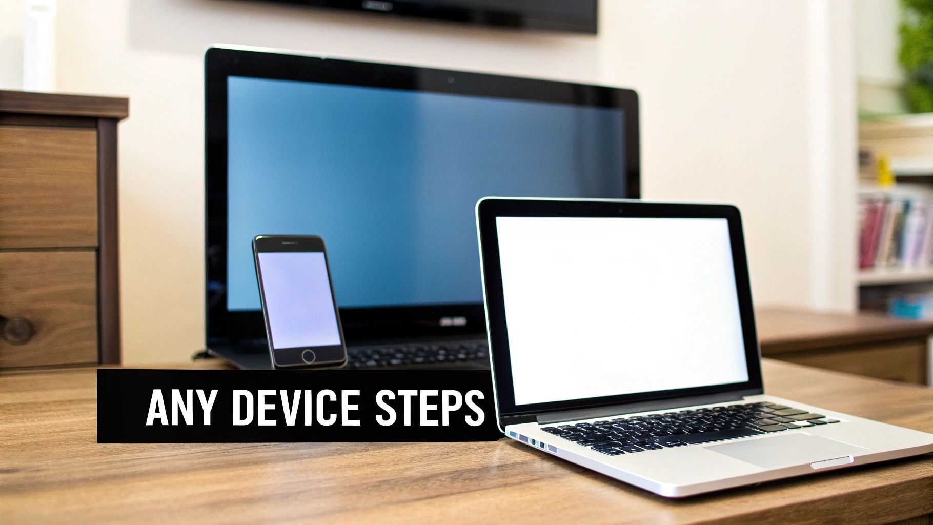 A wooden desk with a laptop, a smartphone, and a large monitor, indicating a multi-device setup.