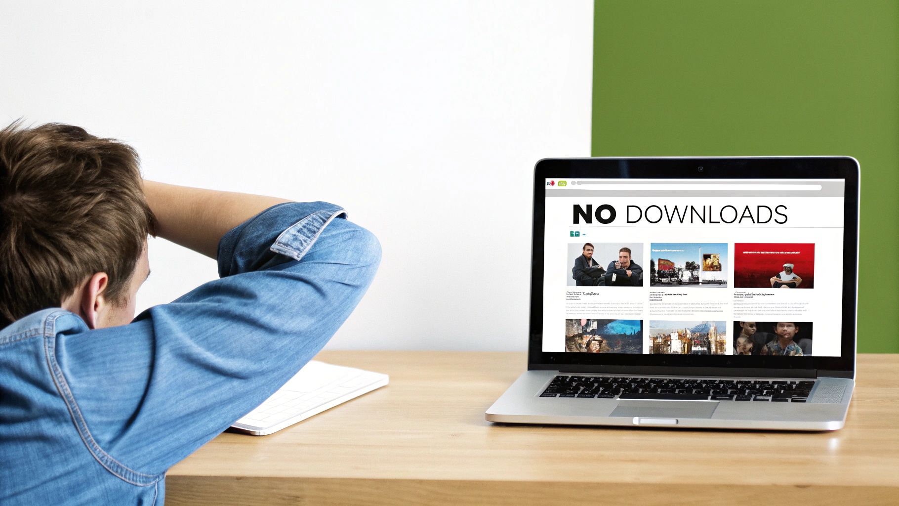 Rear view of a person in a denim shirt looking at a laptop displaying a 'NO DOWNLOADS' website.