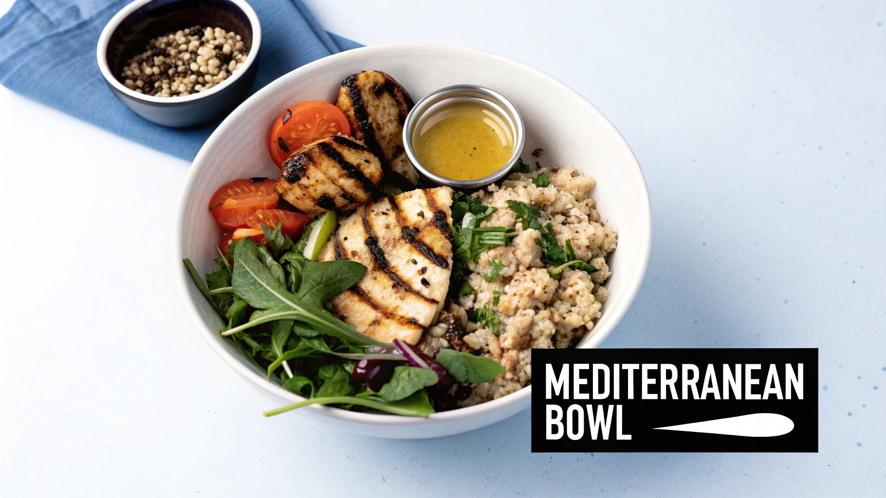 A vibrant Mediterranean bowl featuring grilled halloumi, quinoa, fresh tomatoes, and mixed greens, served with dressing.