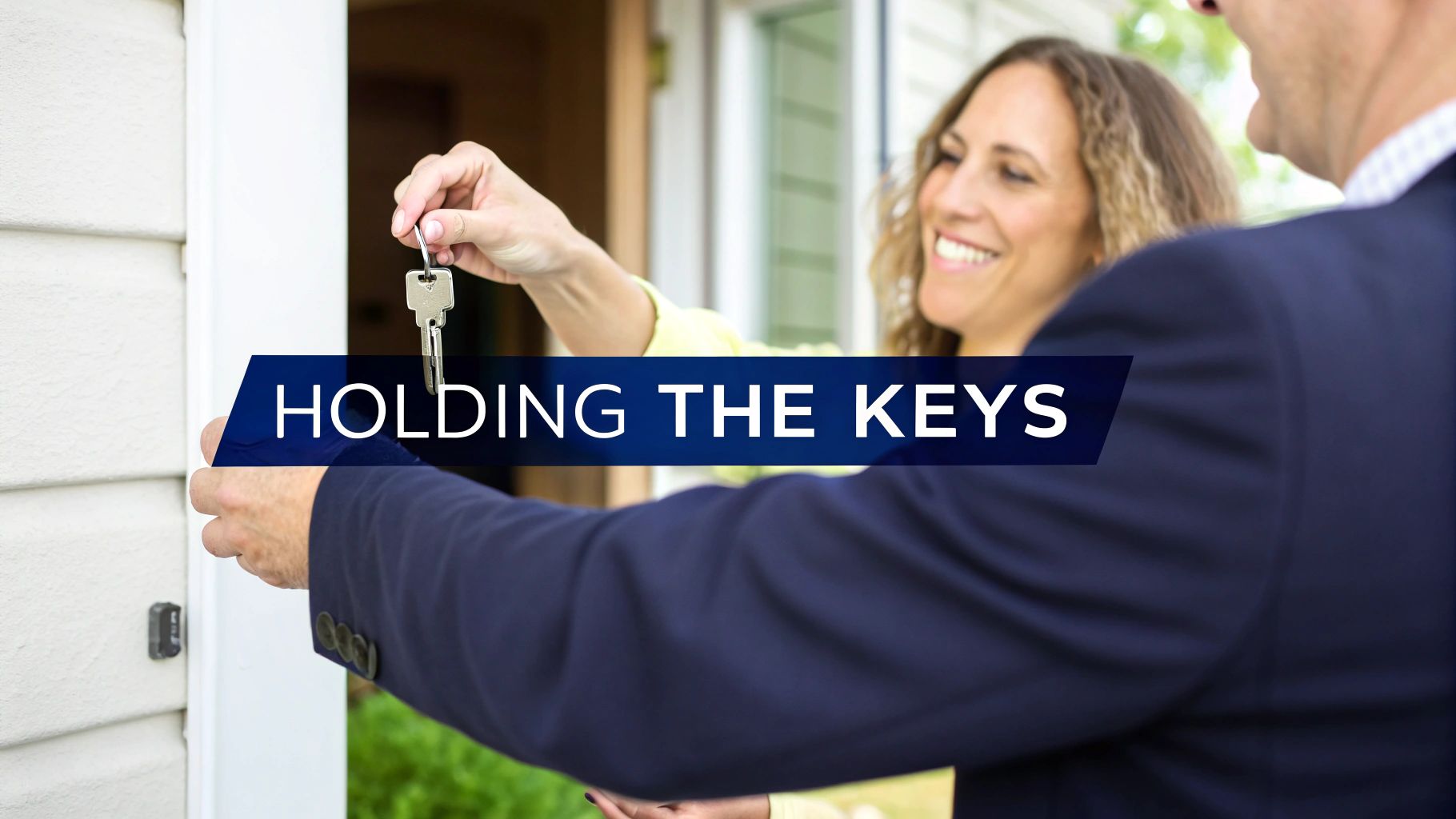 A smiling woman hands a set of house keys to a man, symbolizing a home purchase.