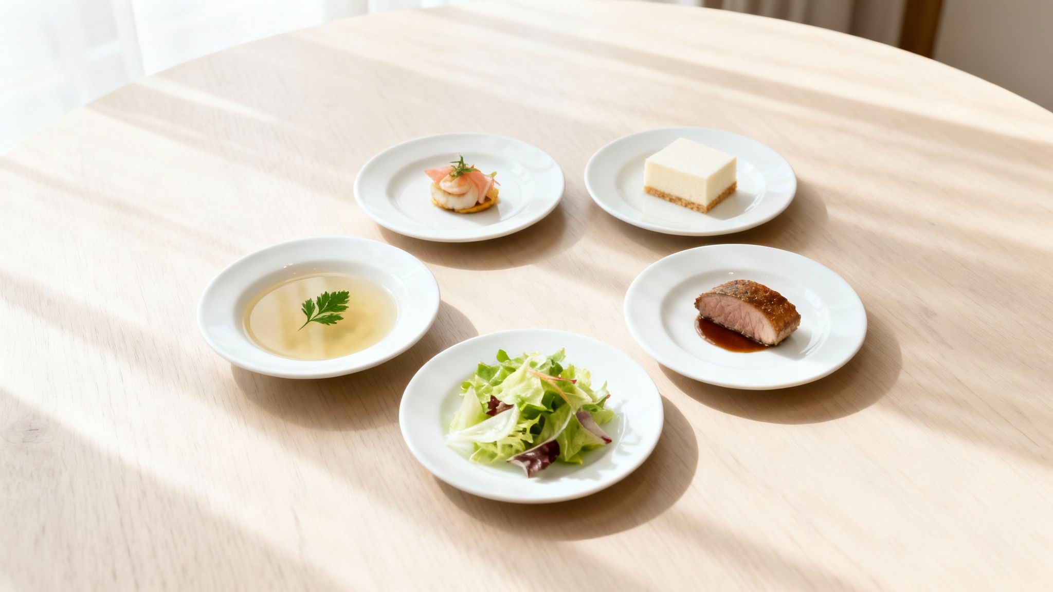 Elegantly presented five-course meal with soup, appetizer, salad, main, and cheesecake on a light wood table.