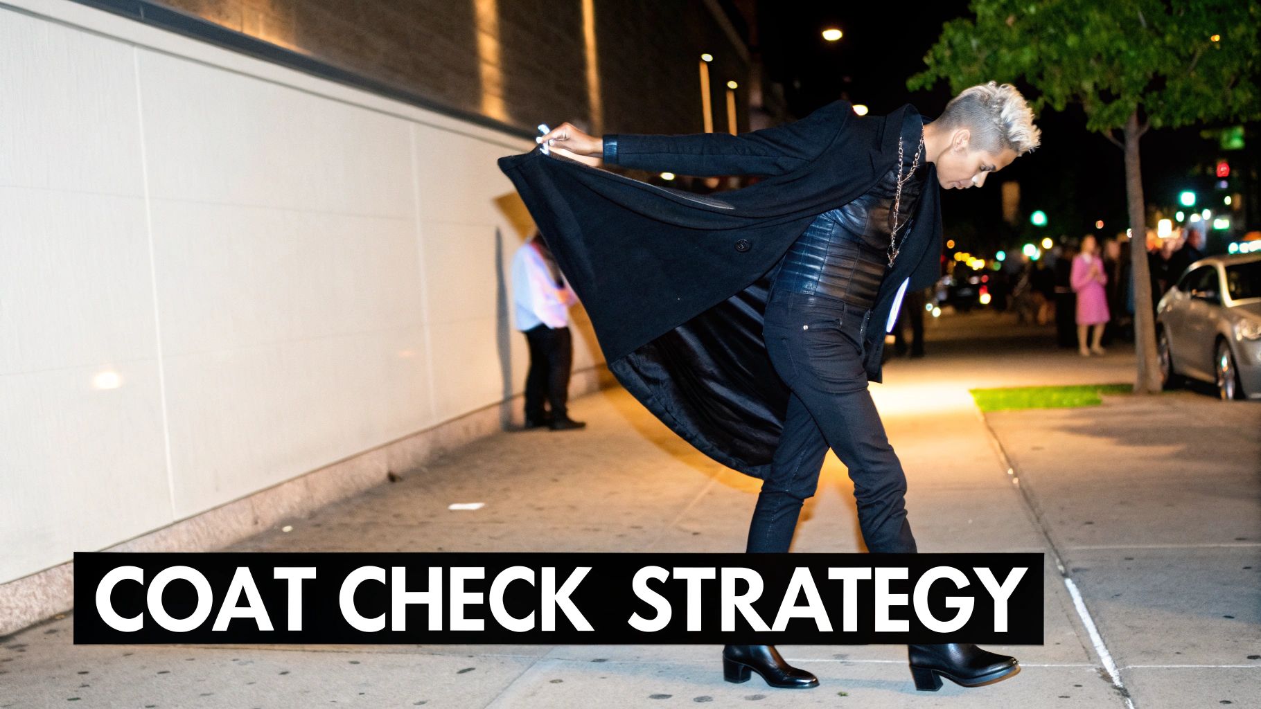 A stylish person in a black coat and leather top walks on a sidewalk at night.