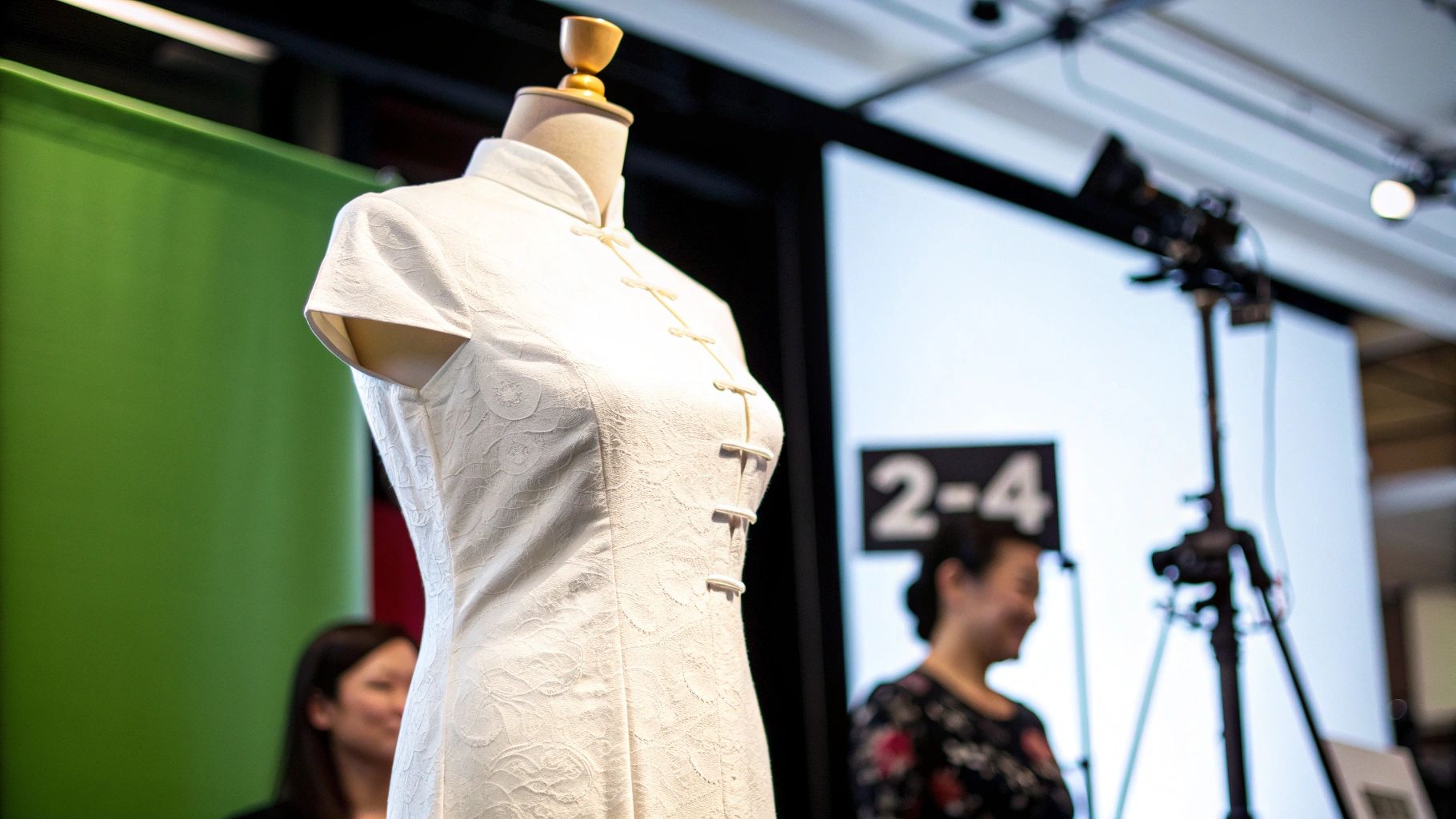 Elegant white Qipao-style dress with intricate patterns on a mannequin, against a green screen background.