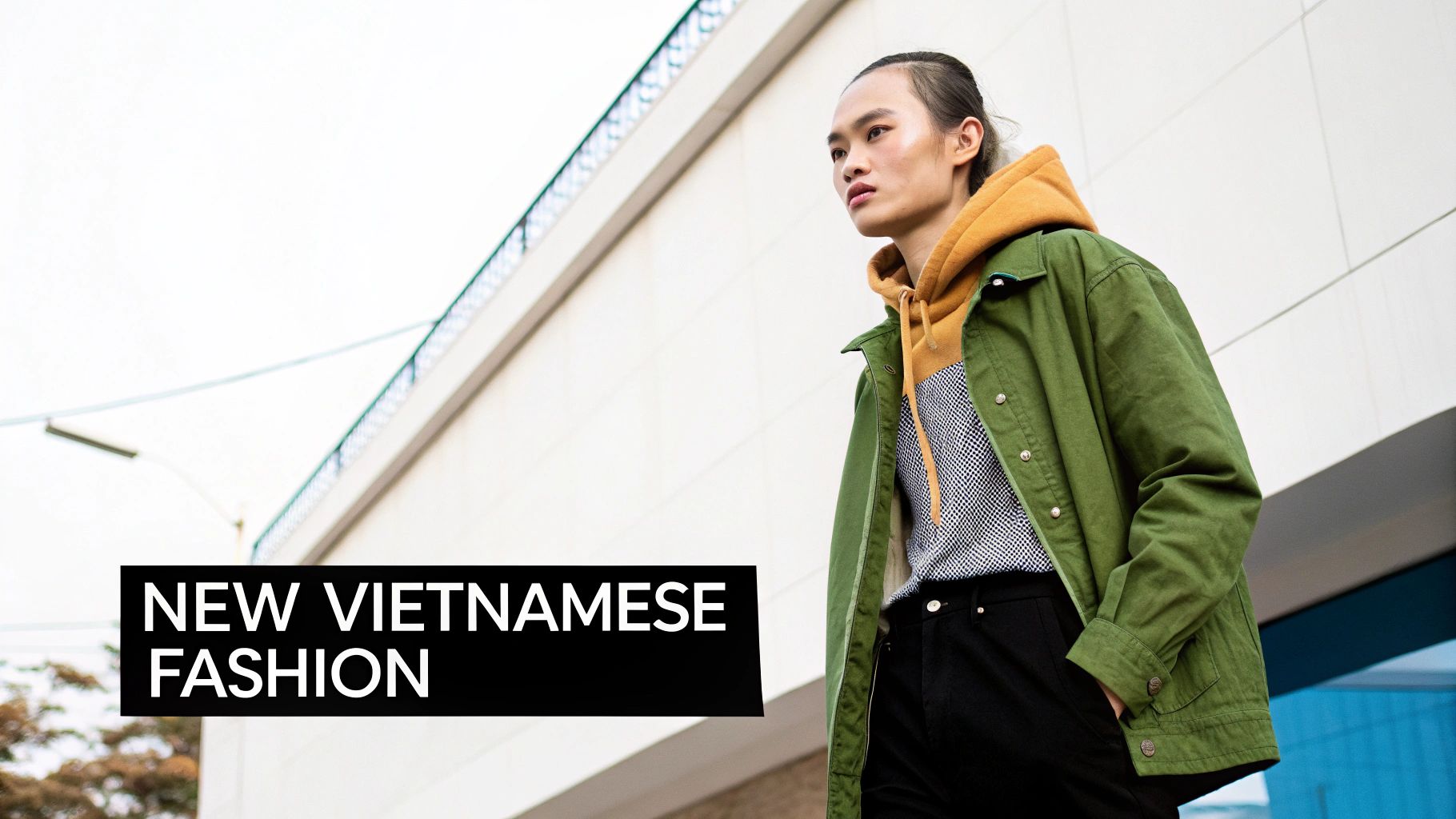 A stylish person in an olive green jacket and yellow hoodie, showcasing new Vietnamese fashion.