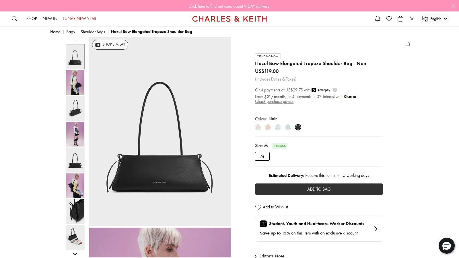 A woman holding a structured black bow purse from CHARLES & KEITH.