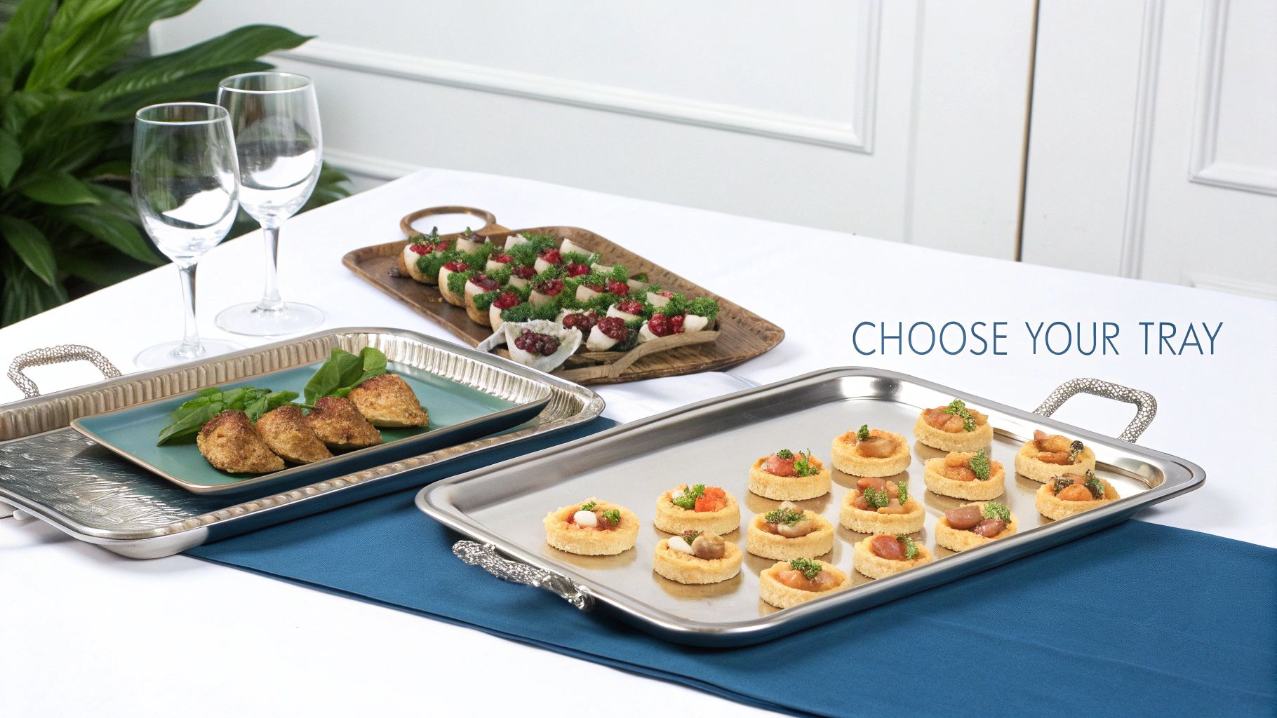 Three stylish serving trays filled with various appetizers and two wine glasses on a white tablecloth.