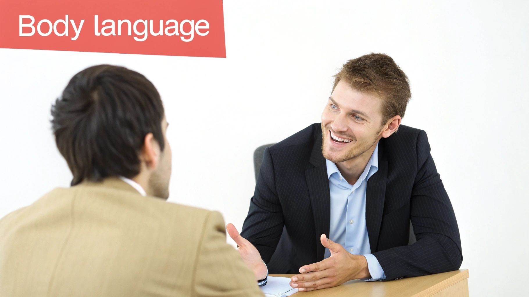 Two professional men discussing, one smiling and gesturing, illustrating body language during a job interview.