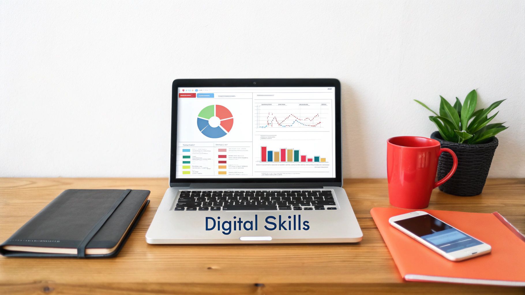 A laptop displaying data charts on a wooden desk with 'Digital Skills' text, alongside notebooks, a phone, and a coffee mug.