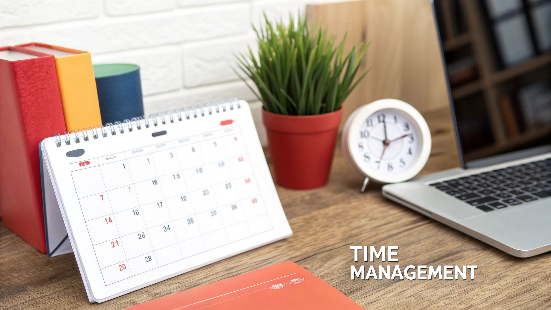 A clean desk setup with a calendar, laptop, clock, and books, emphasizing time management.