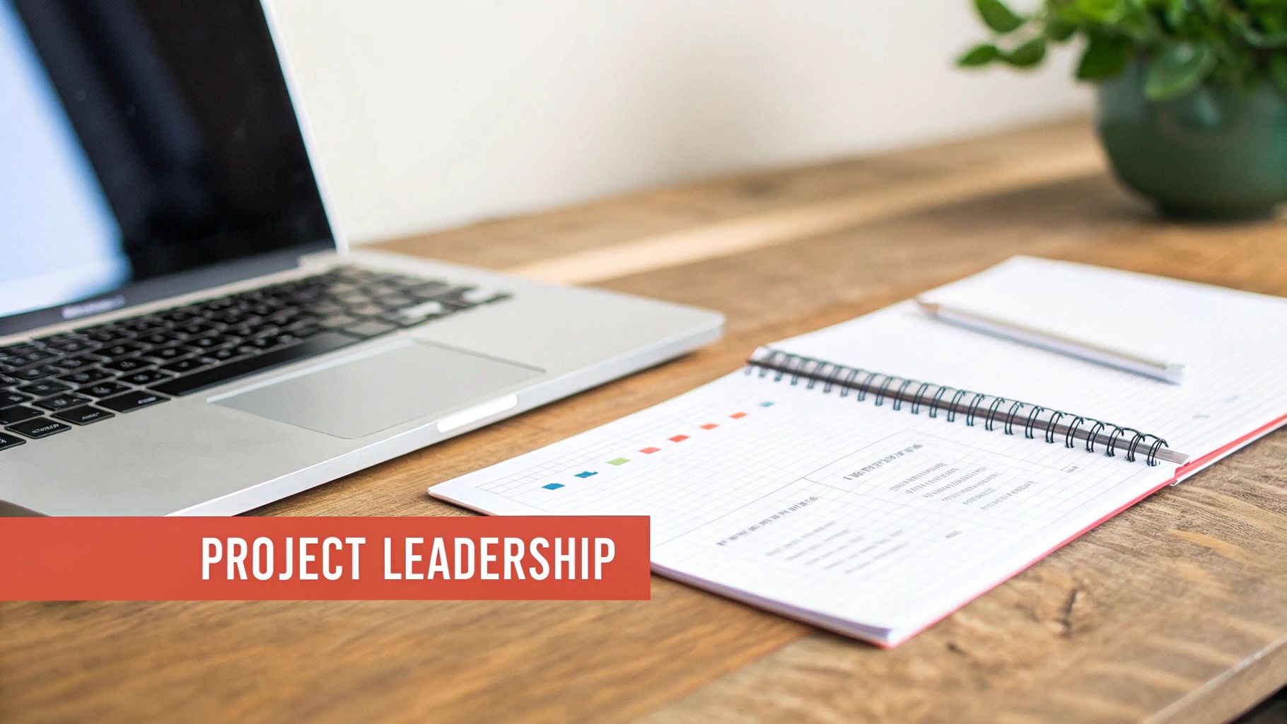 An organized workspace featuring a laptop, open notebook, and pencil on a wooden desk, with 'PROJECT LEADERSHIP' text.