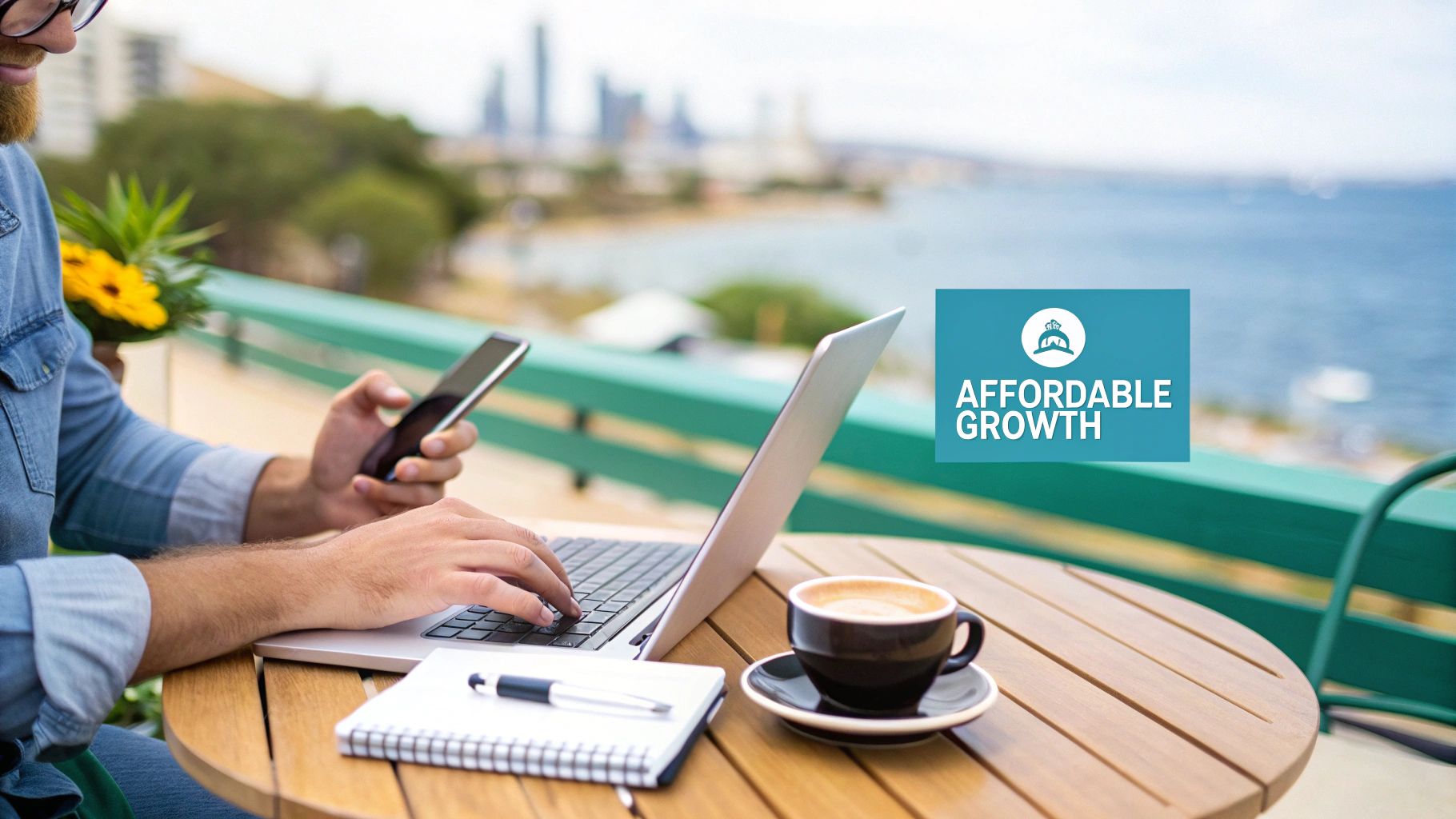Man working on laptop and phone at an outdoor table with coffee and an 'Affordable Growth' sign.