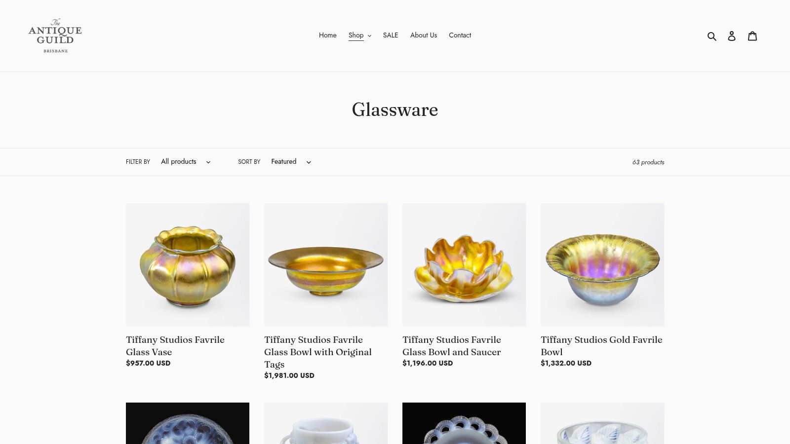 A screenshot of The Antique Guild website's glassware section, showing a collection of antique coloured glass vases and bowls.