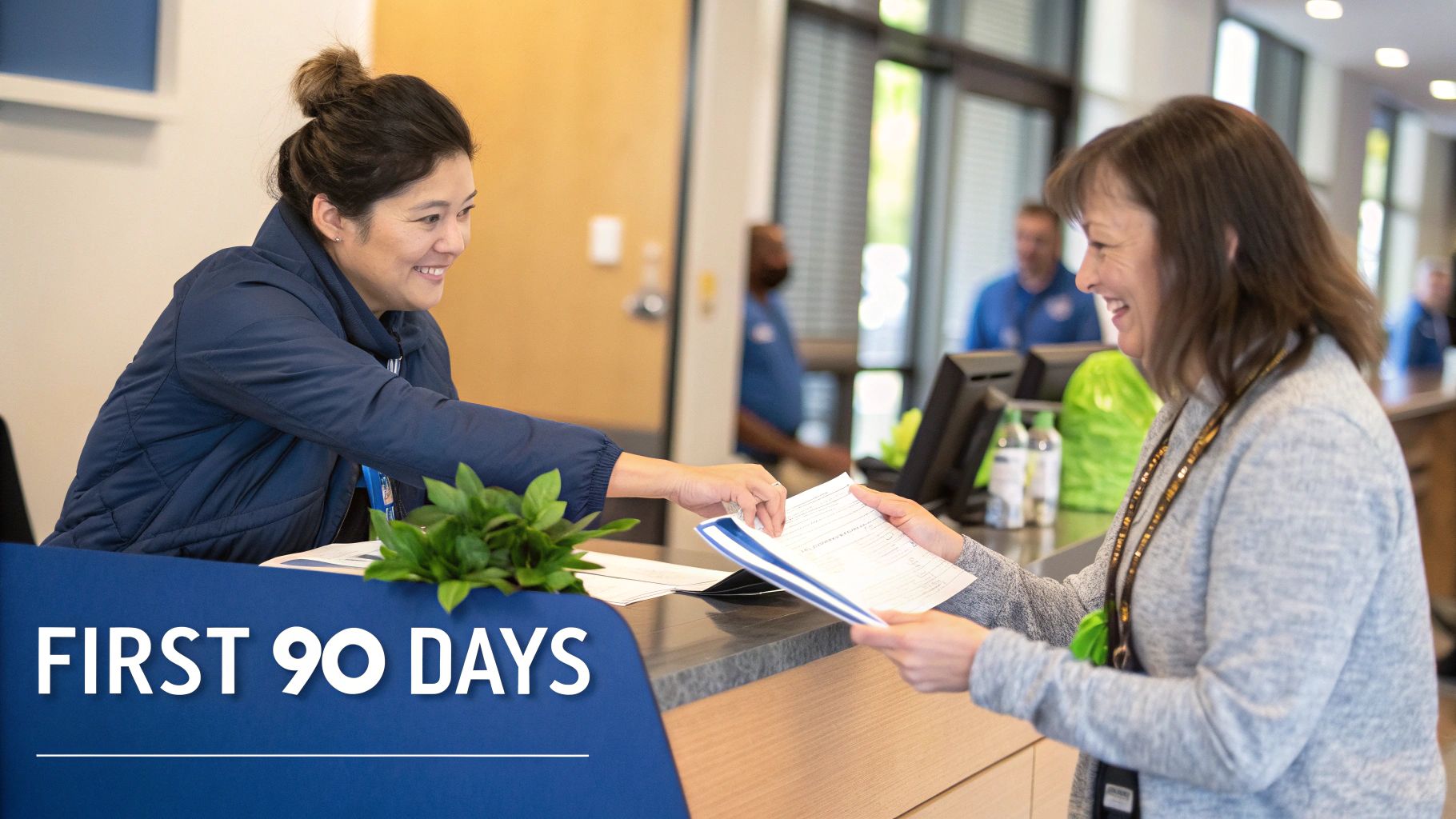 Two smiling women exchanging documents at an office counter, symbolizing new employee onboarding.