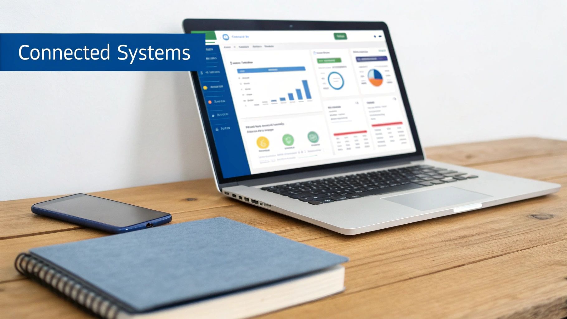 A laptop displaying a data dashboard, a smartphone, and a notebook on a wooden desk with a 'Connected Systems' banner.