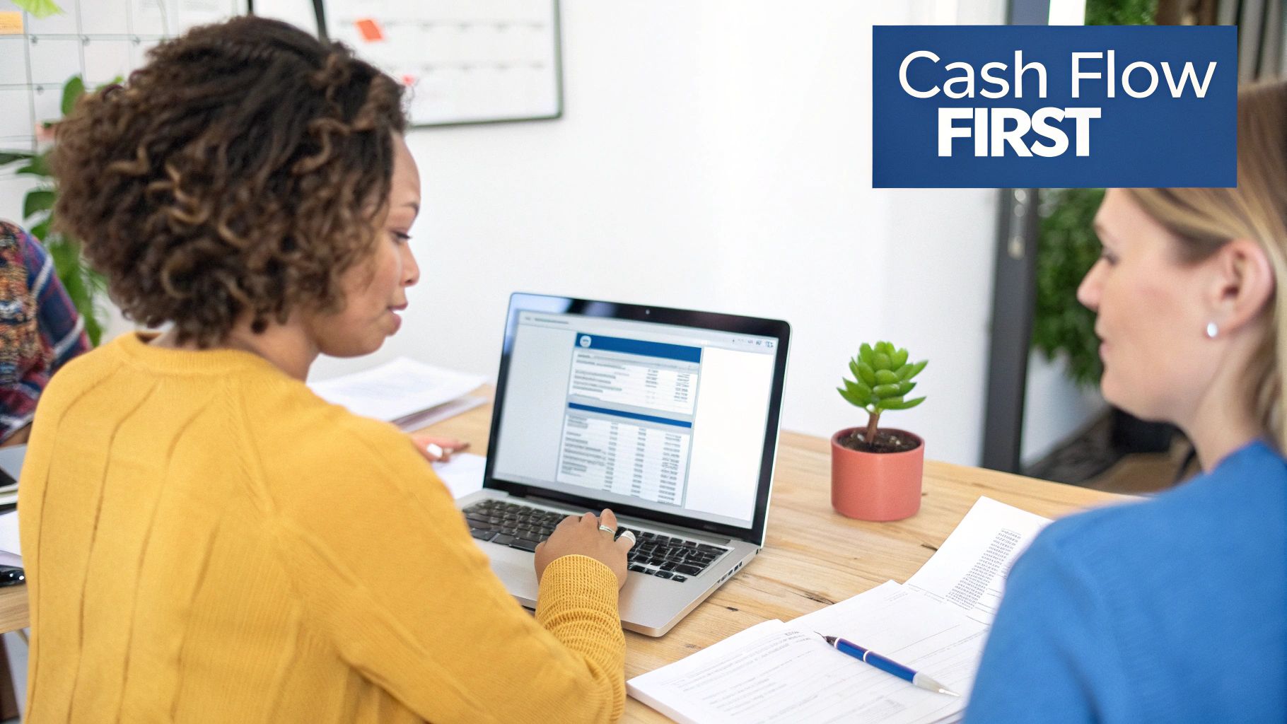 Two women analyzing financial data on a laptop, focusing on cash flow projection.