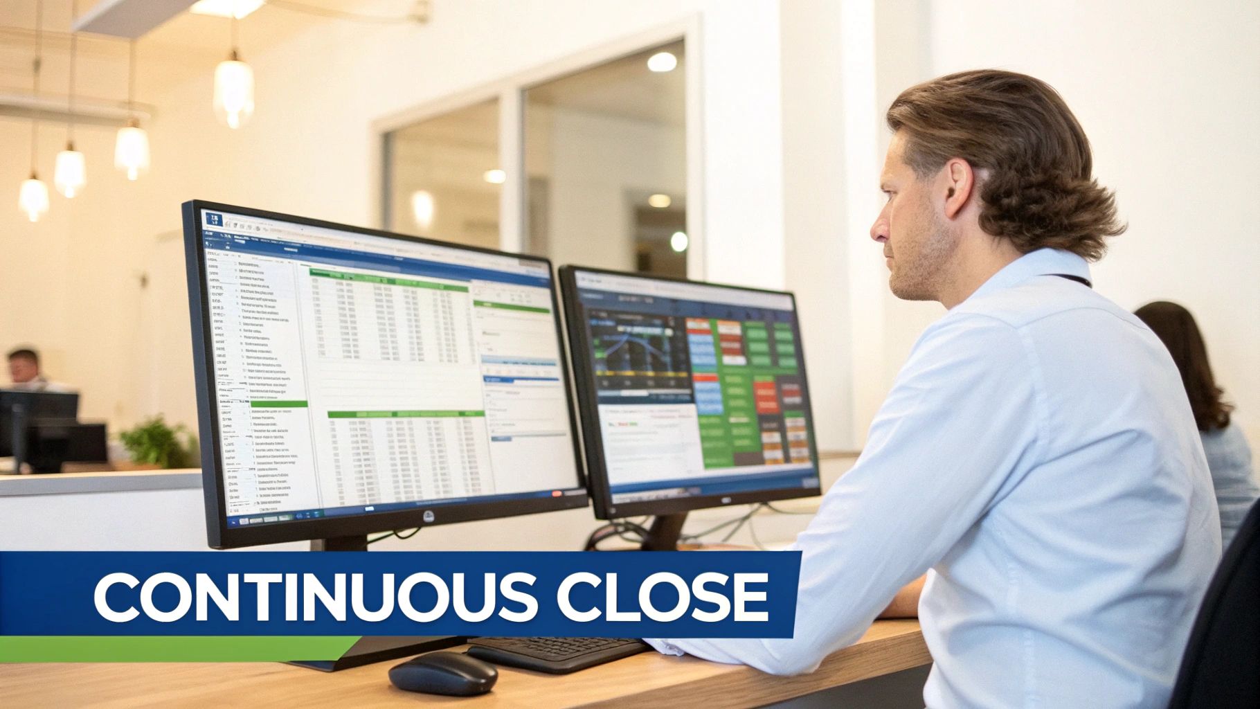 A man in an office looks at two computer monitors displaying financial data and spreadsheets.