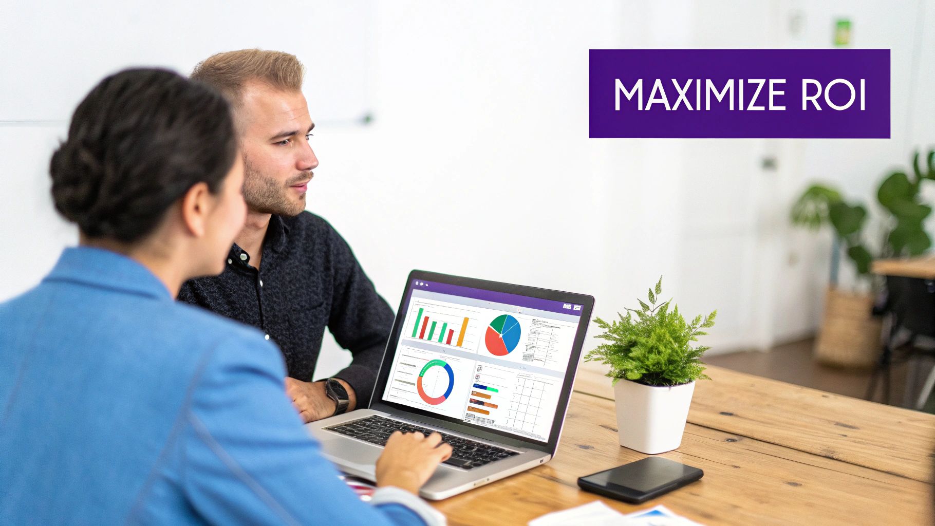 Colleagues reviewing business data visualizations on a laptop to maximize ROI.