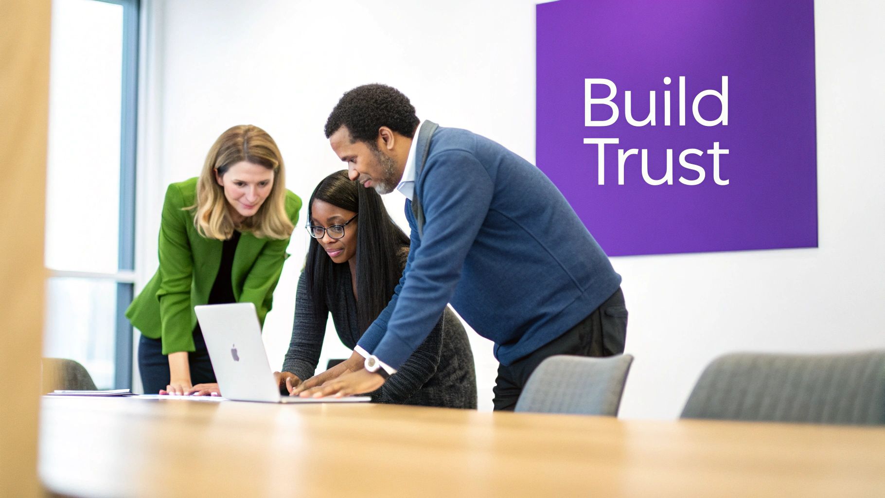 Three diverse business professionals collaborate around a laptop in a modern office, fostering trust.