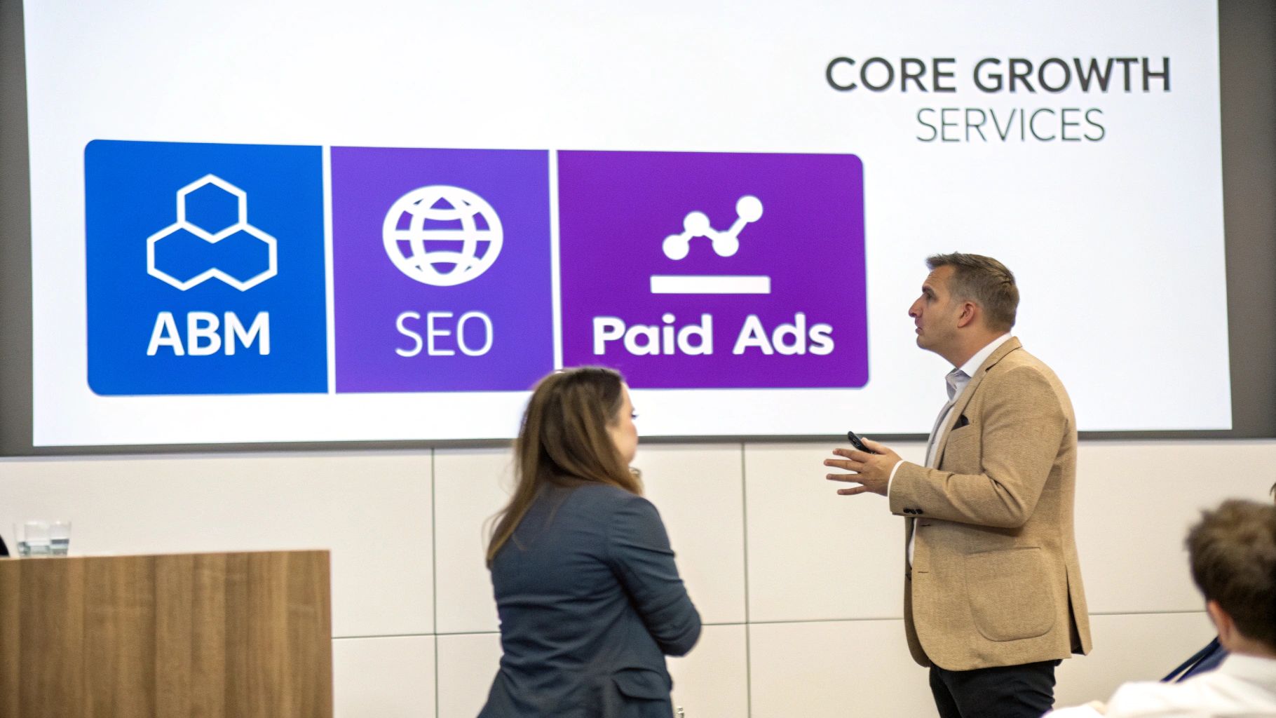 Business professional presenting core growth services including ABM, SEO, and paid ads to team