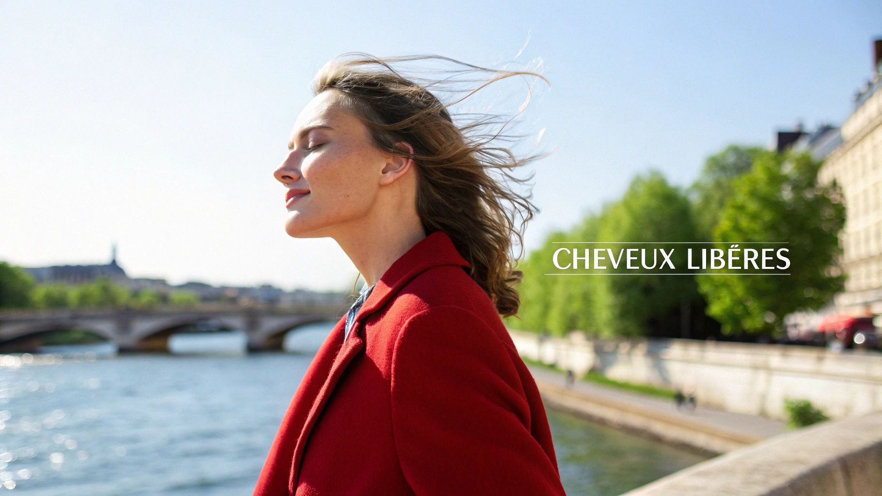 Une femme aux cheveux longs et ondulés sourit en tenant délicatement une mèche de ses cheveux.