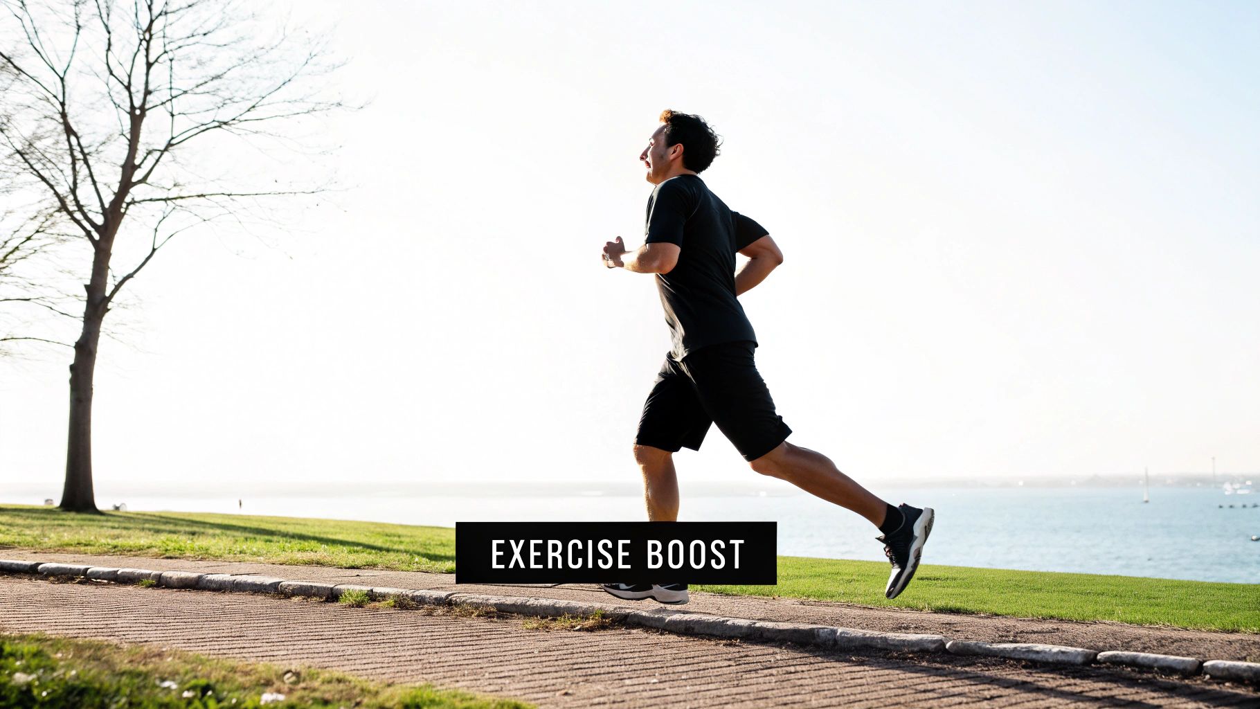 A man in black athletic wear runs on a paved path beside a grassy hill and the ocean.