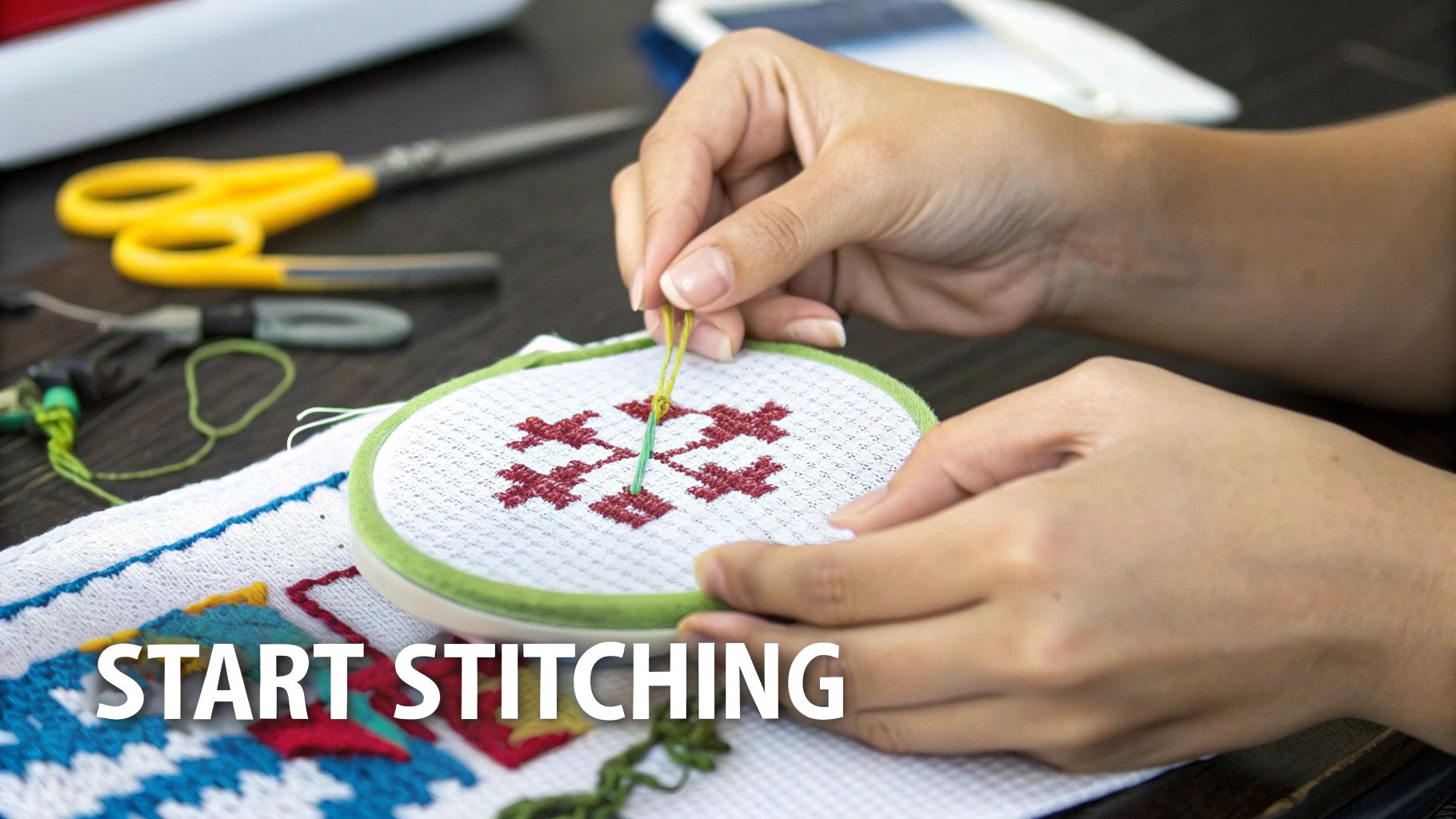 Close-up of hands cross-stitching a red pattern on white fabric in an embroidery hoop.