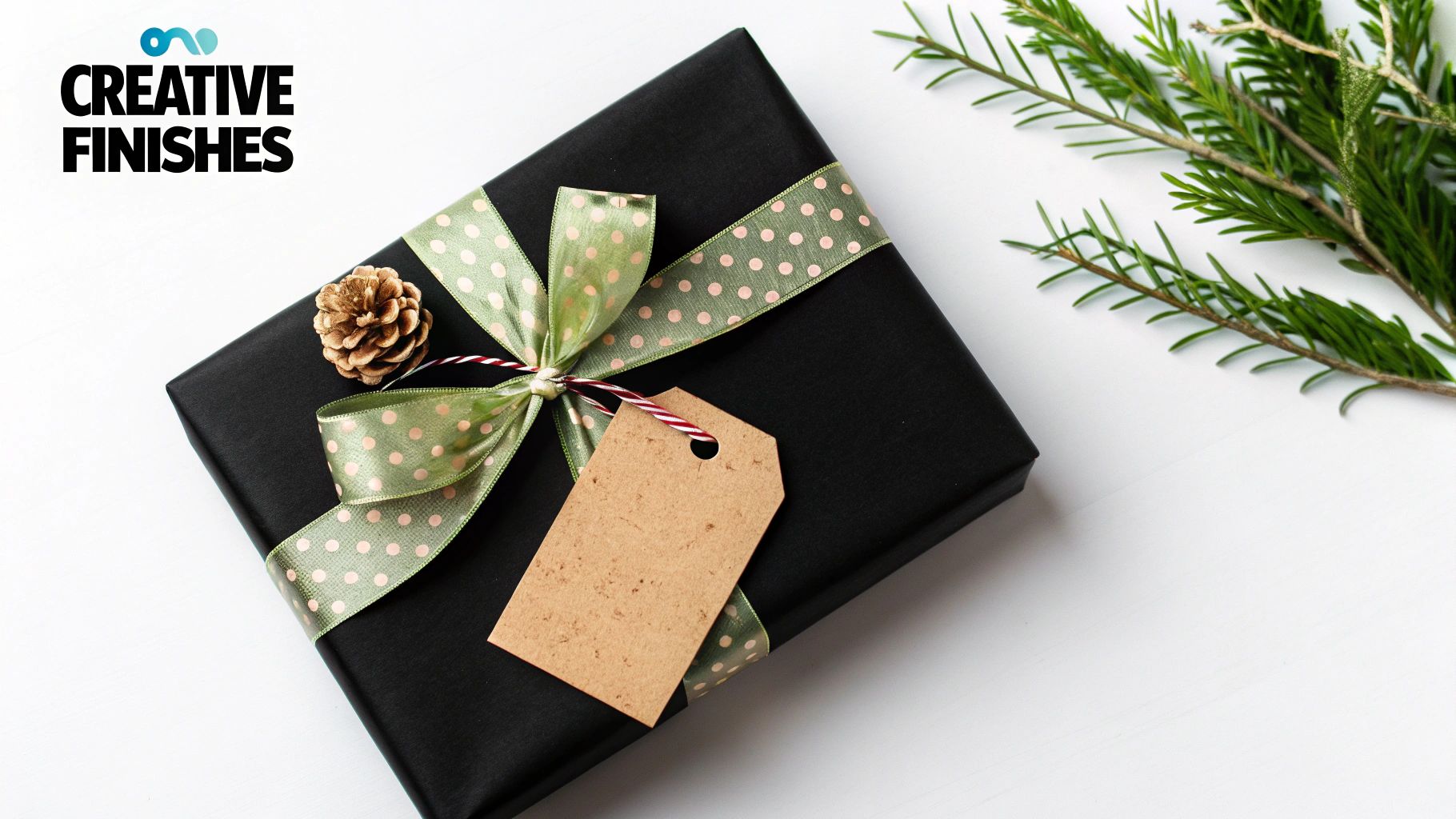 Elegant black gift box wrapped with sage green polka dot ribbon, kraft tag and pine cone