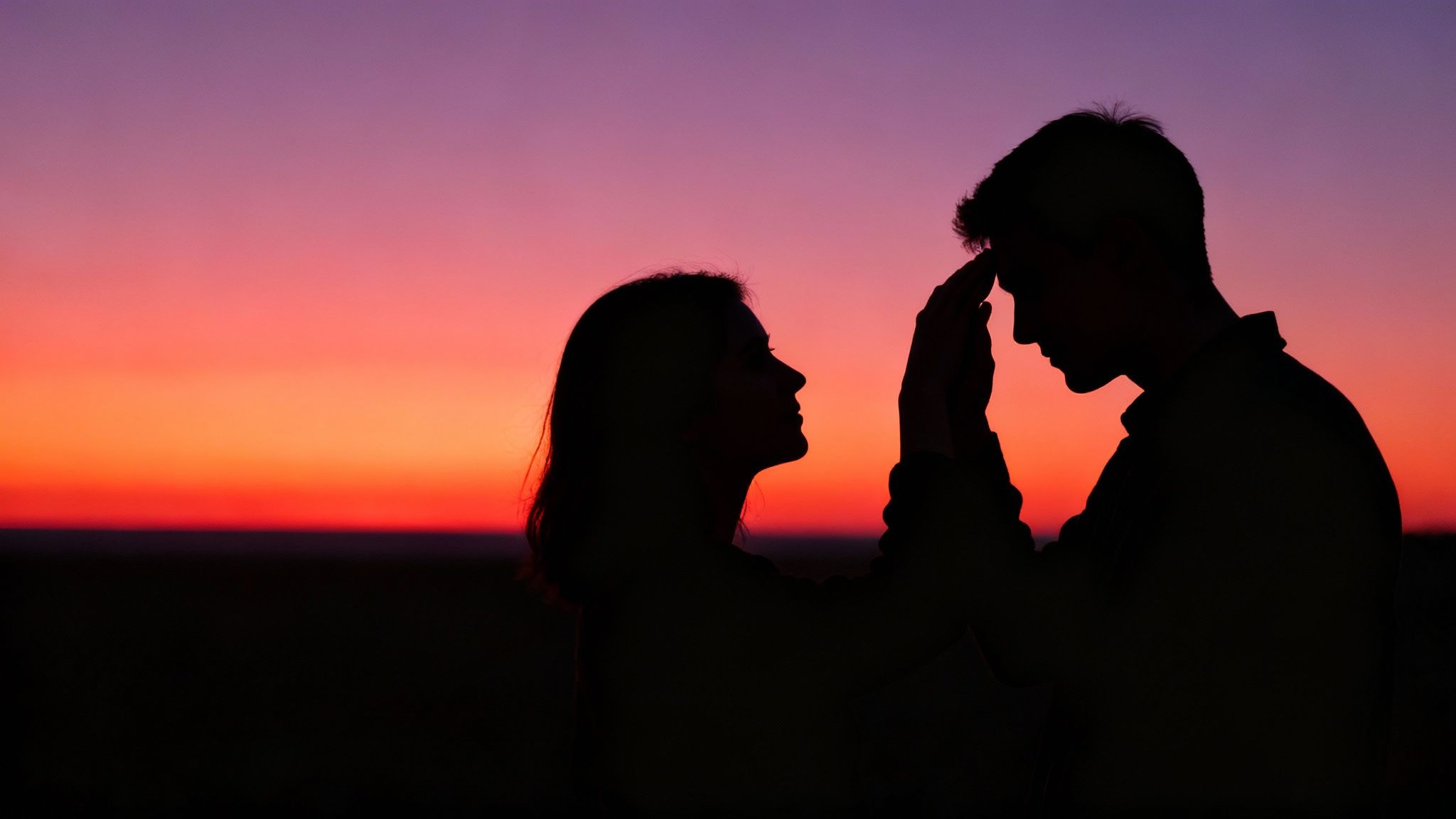 Silhouette of couple facing each other during romantic sunset engagement photo shoot outdoors