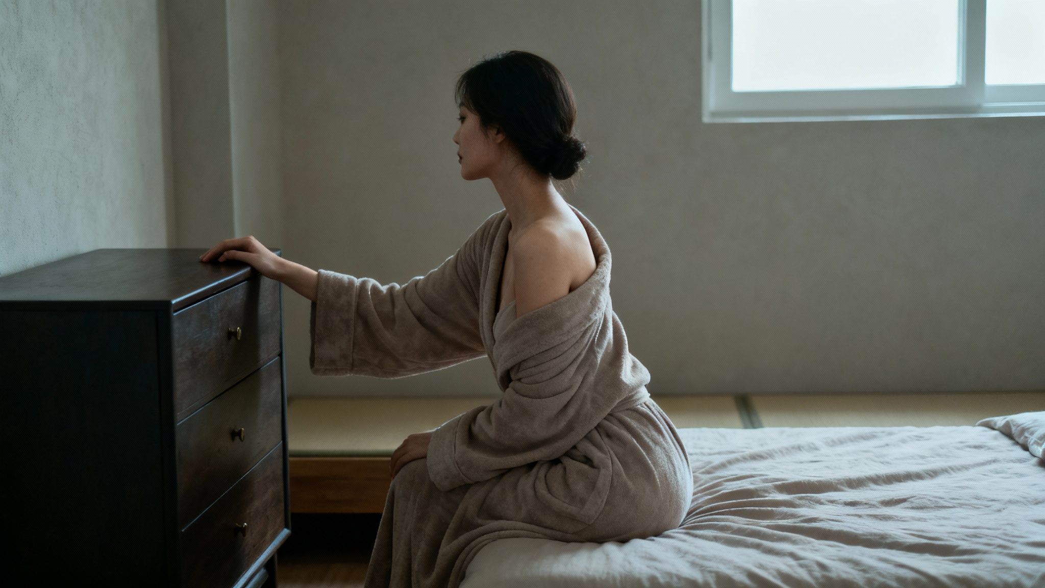 A woman in lingerie posing gracefully on a bed for her at-home boudoir photoshoot.