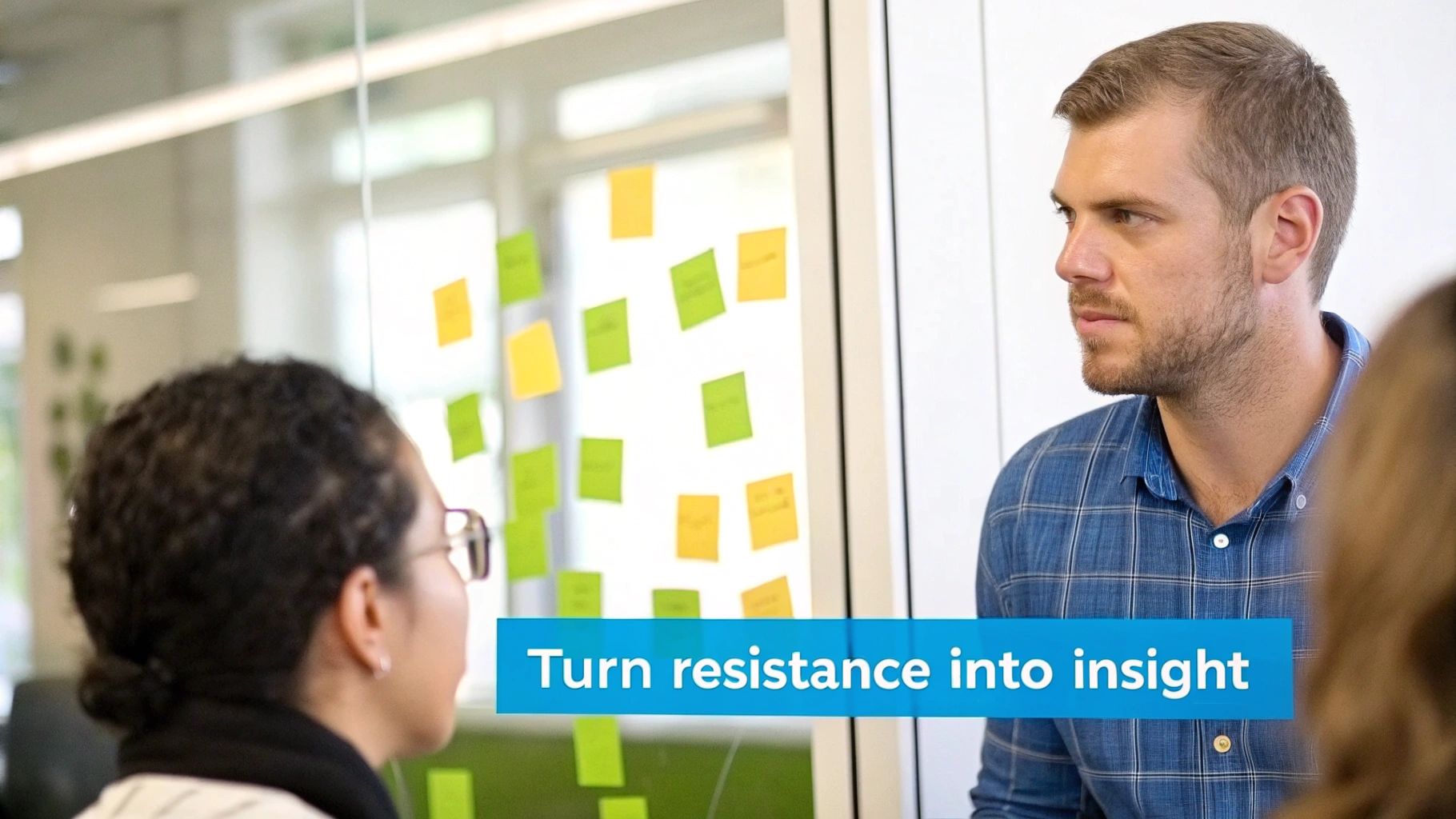 Two people collaborating in a meeting, with sticky notes on a glass wall in the background.