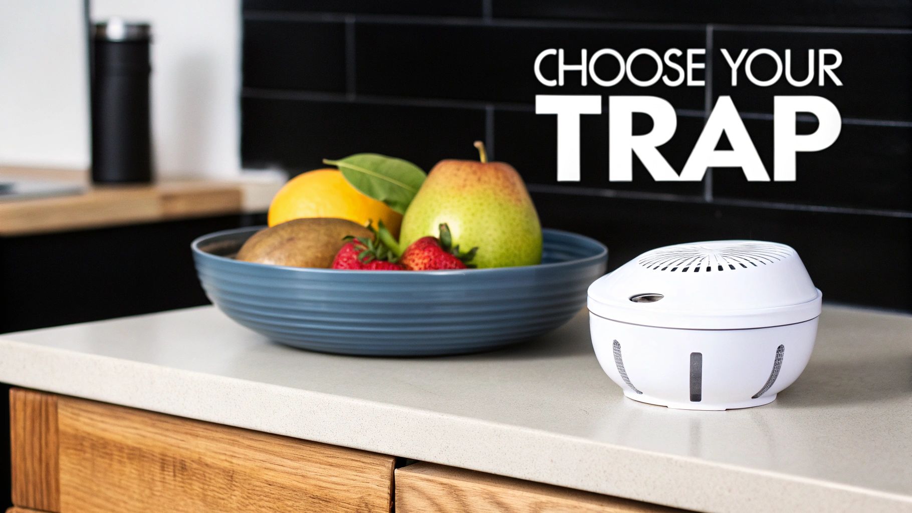 A white fruit fly trap device sits next to a bowl of fresh fruit on a modern kitchen counter.