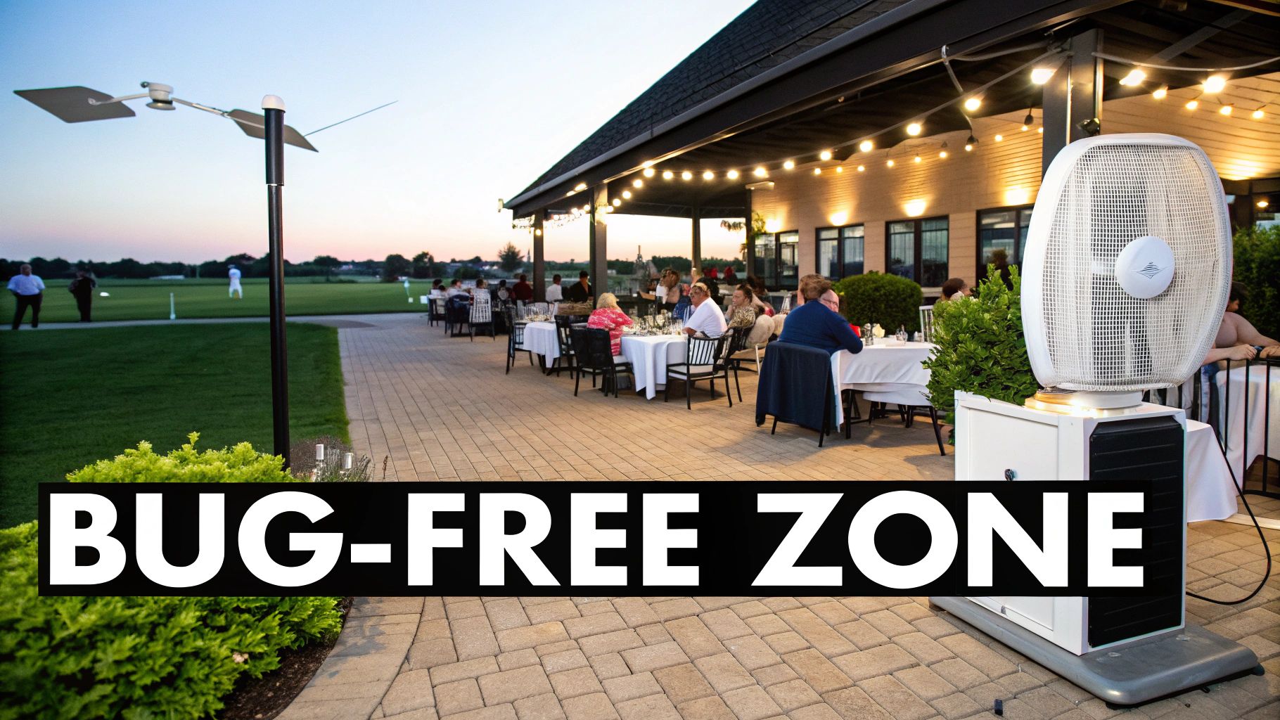 Outdoor patio dining at dusk with a large bug repellent fan, overlooking a golf course.