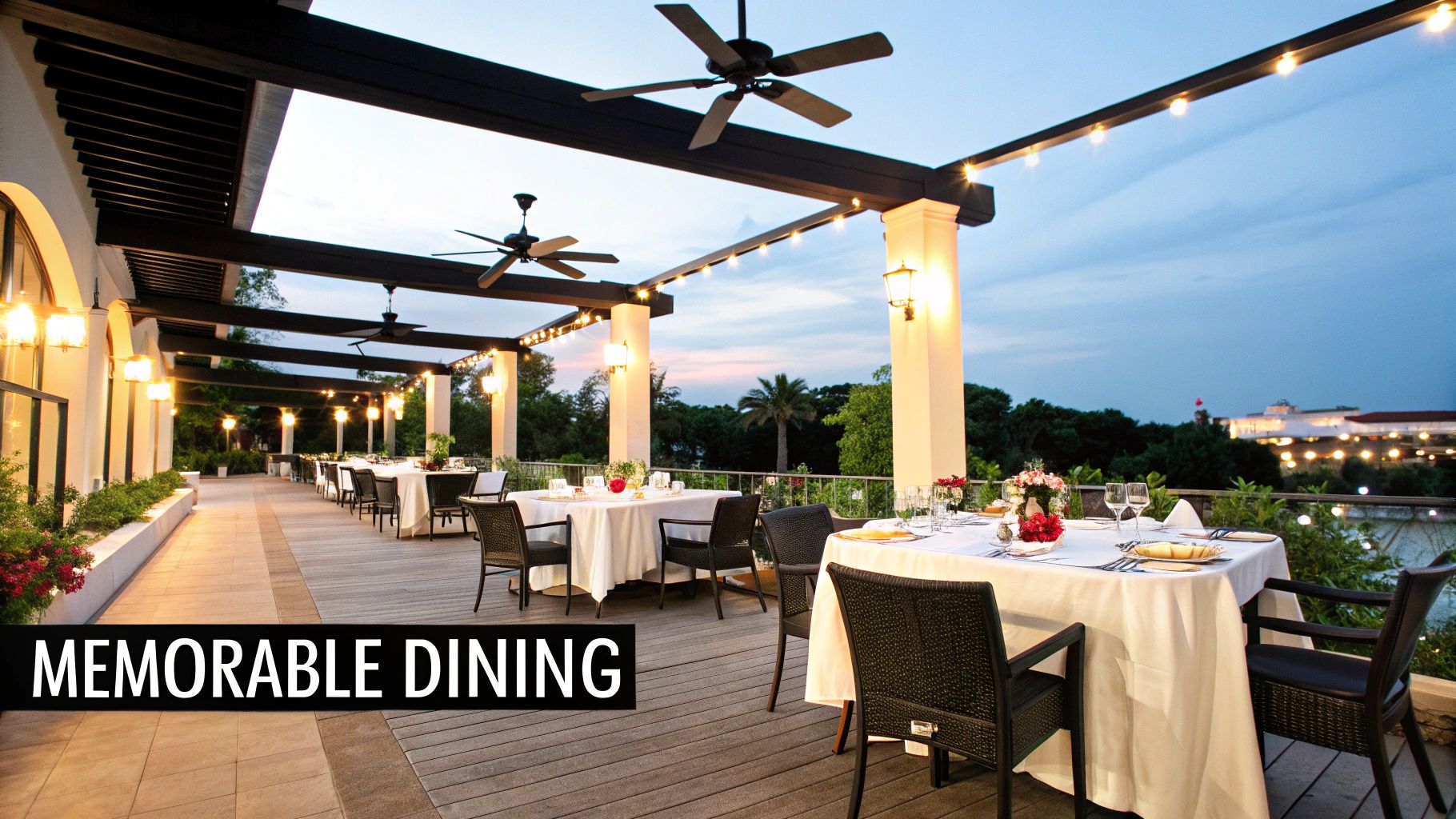 An elegant outdoor restaurant patio with set tables, ambient lighting, and ceiling fans at twilight.