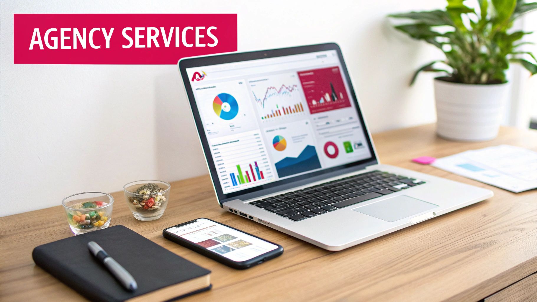 A desk with a laptop displaying data analytics, a smartphone, notebook, and 'AGENCY SERVICES' banner.