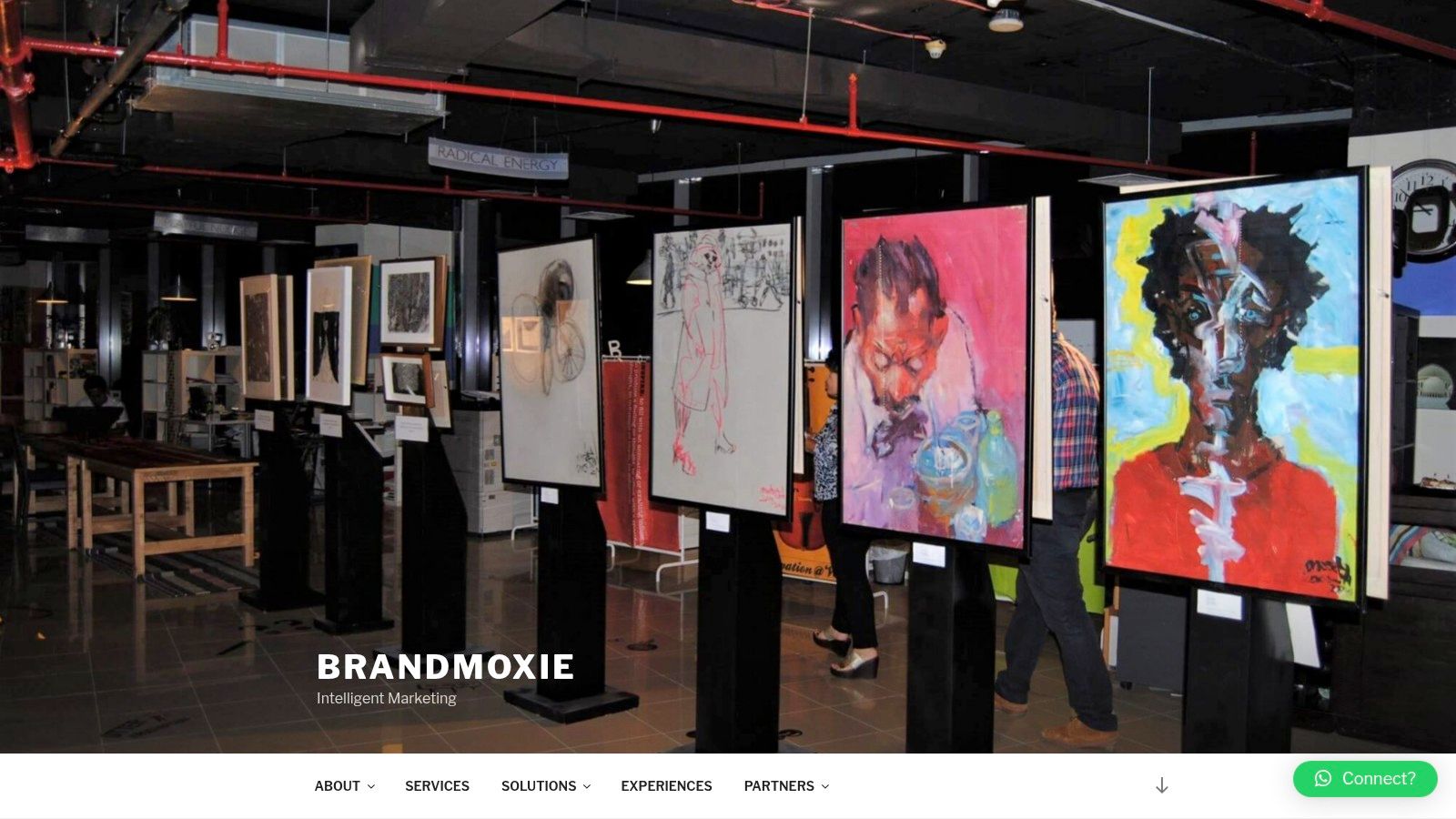 An art exhibition event hosted by BrandMoxie, showing people networking in a gallery setting.