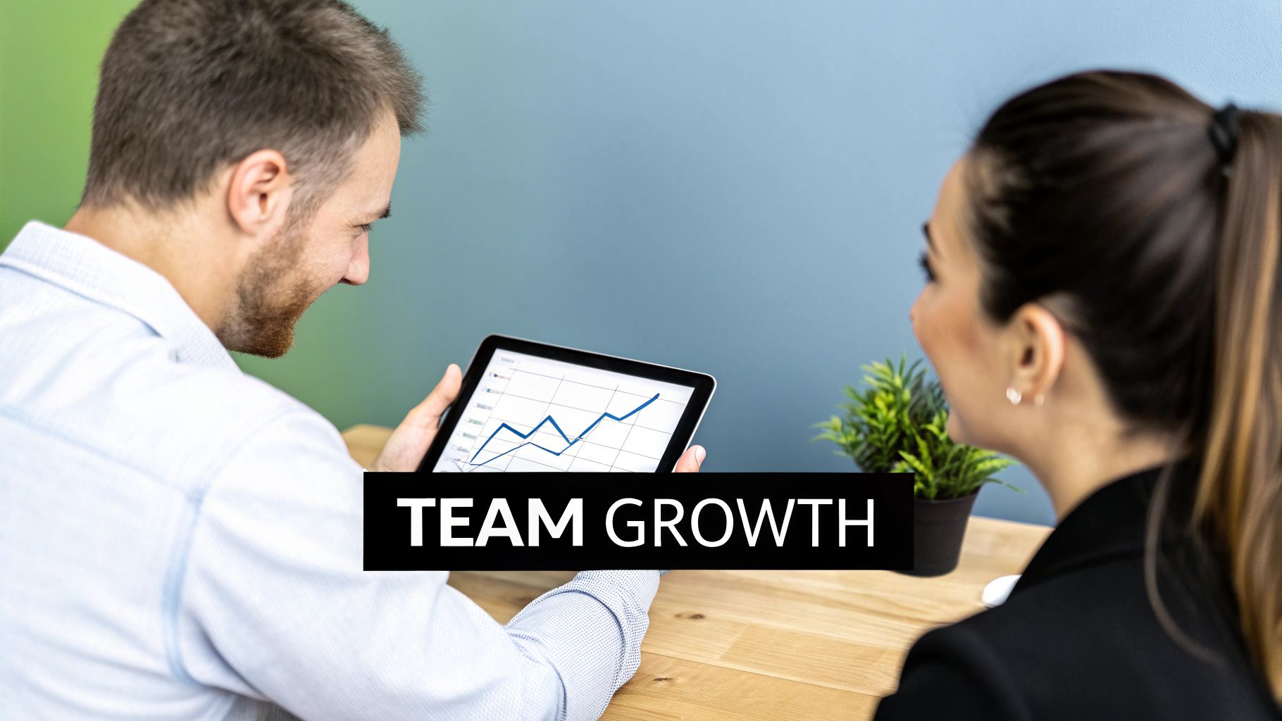 Two smiling colleagues reviewing a growth chart on a tablet, symbolizing team development and success.