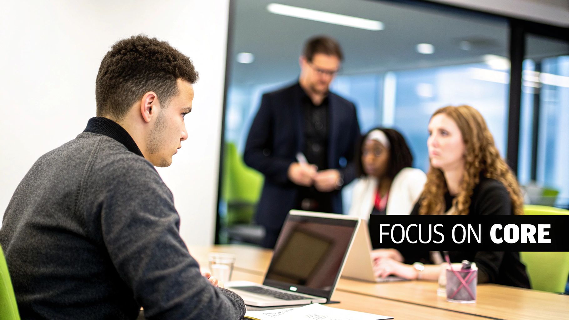 Diverse business professionals collaborate in a modern office meeting, focusing on core tasks.