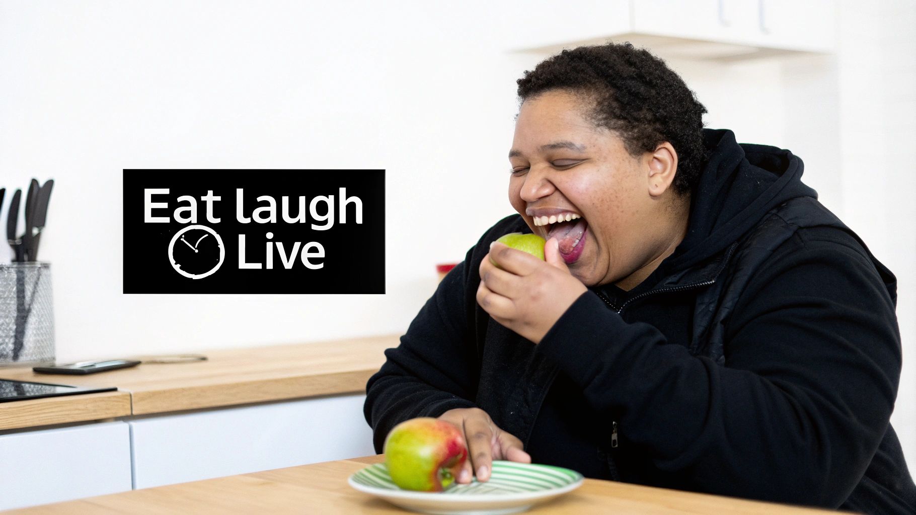 A person joyfully eats a green apple, with a 'Eat laugh Live' sign on the wall.