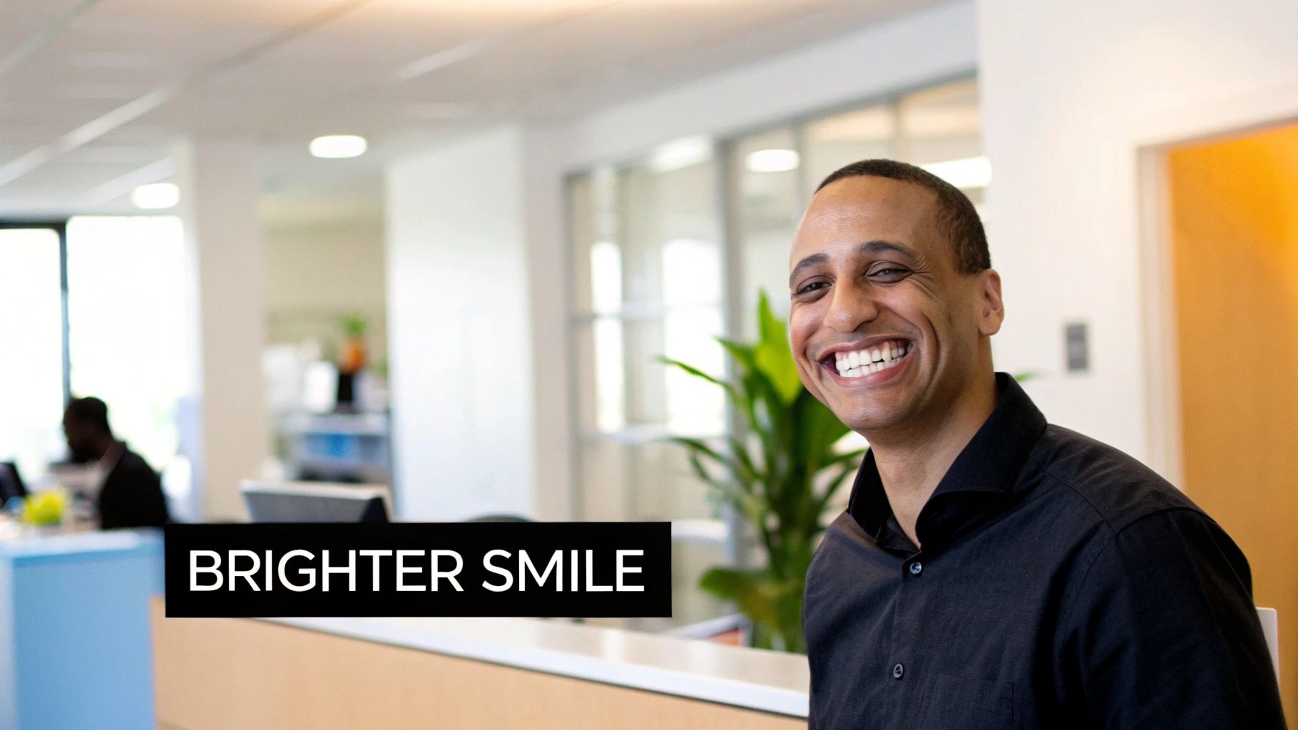 A smiling man with bright white teeth in a professional office setting.