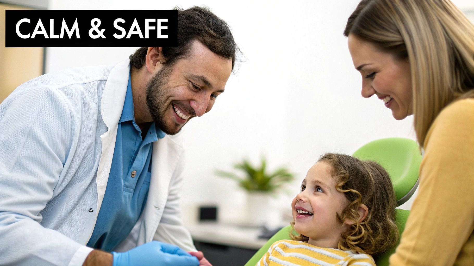 A smiling male dentist, parent, and happy young child in a dental chair, creating a calm and safe experience.